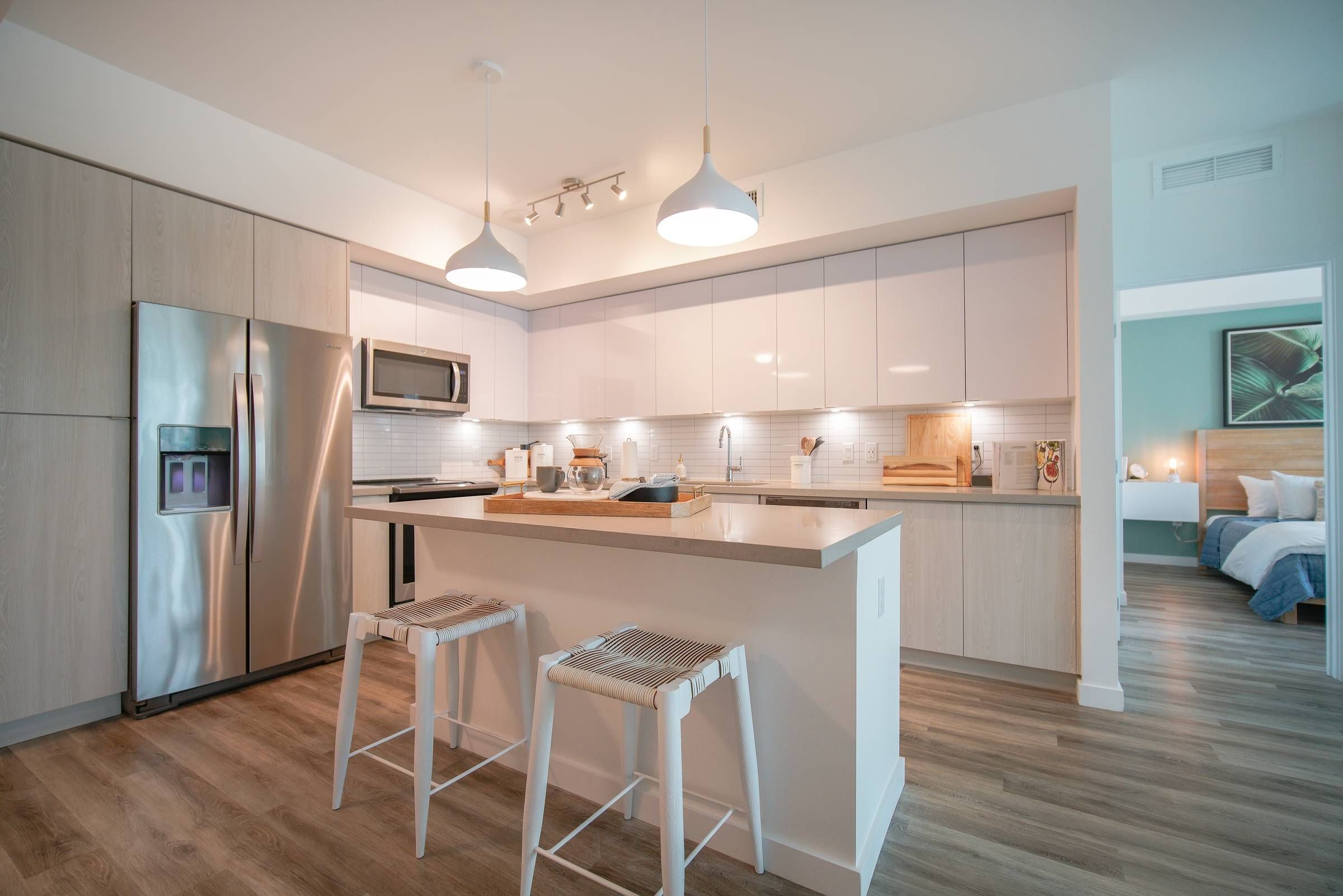 Bask resident kitchen with ample cabinet space, floating kitchen island with seating, and stainless steel appliances.