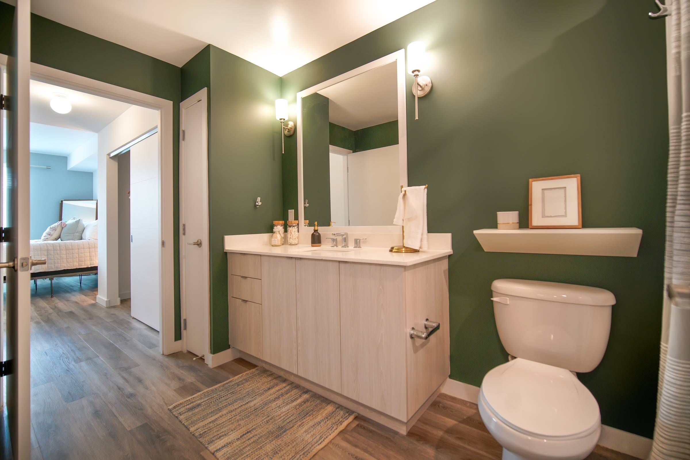 Bask bathroom with toilet and cabinet with green walls.