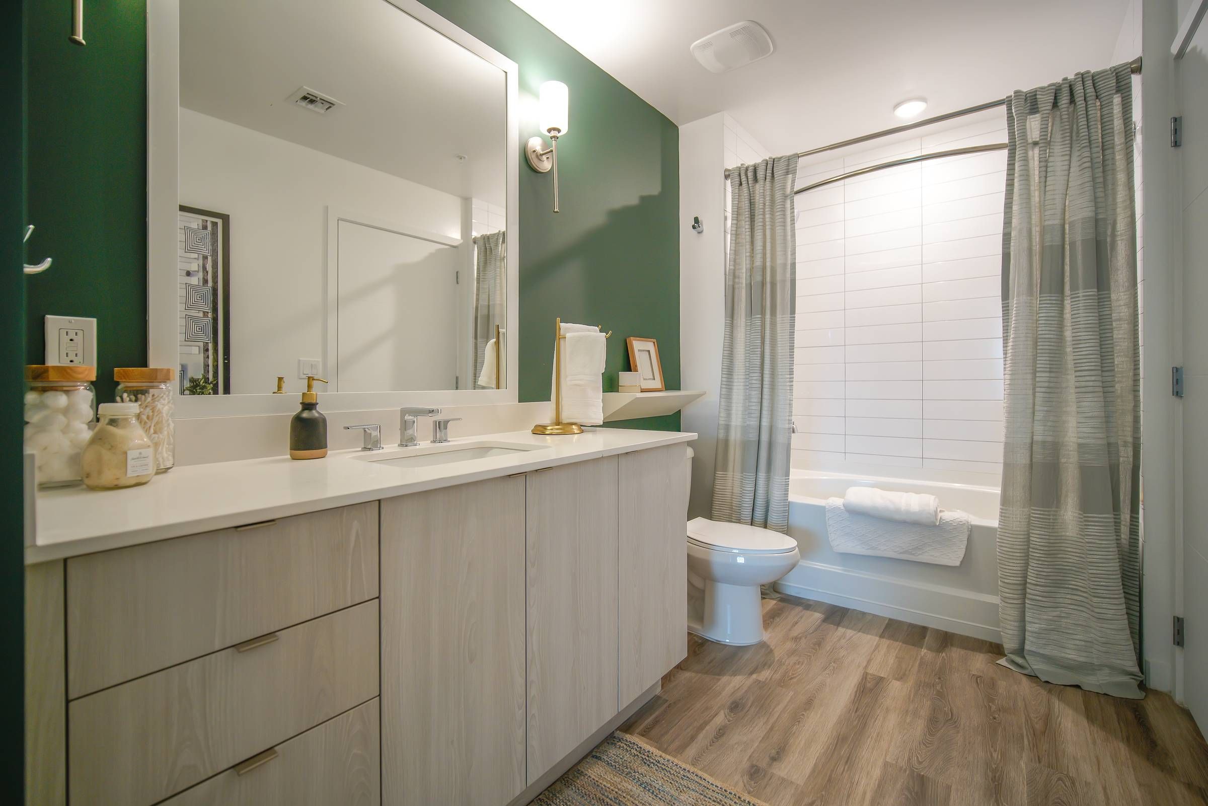 Bask bathroom with toilet, shower/bath, ample cabinet space, and green walls.