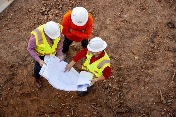 Aerial view of construction team looking at a set of blueprints