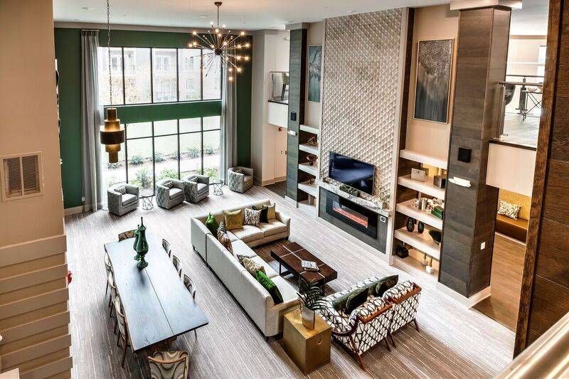 An expansive clubroom at Alta at Jonquil with two-story ceilings, a cozy seating area, a dining space, and a fireplace, all bathed in natural light from large windows.