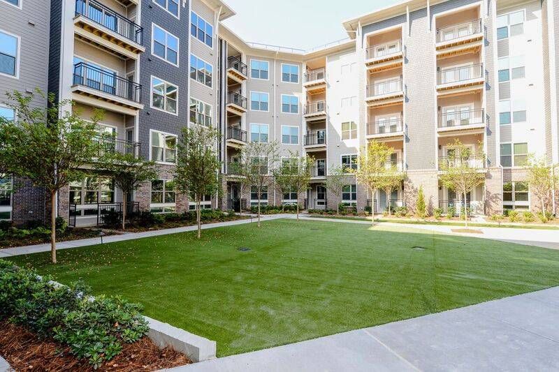A lush courtyard with well-manicured lawns and multiple seating areas surrounded by Alta at Jonquil's contemporary apartment buildings.