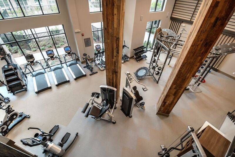 A state-of-the-art fitness center with high ceilings, exposed beams, and a range of exercise equipment at Alta at Jonquil.