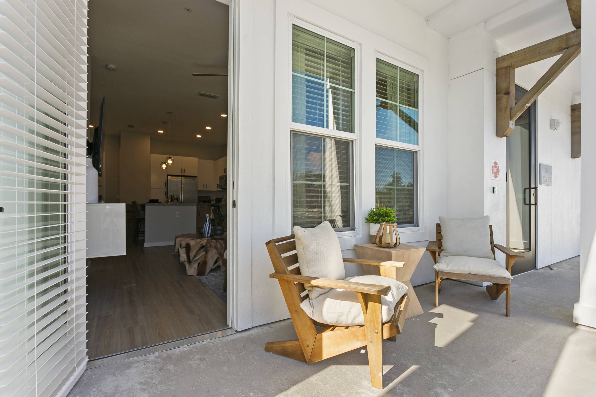 The entrance to the Alta Belleair property showcases a welcoming porch with two wooden rocking chairs and an open door leading to a modern interior.