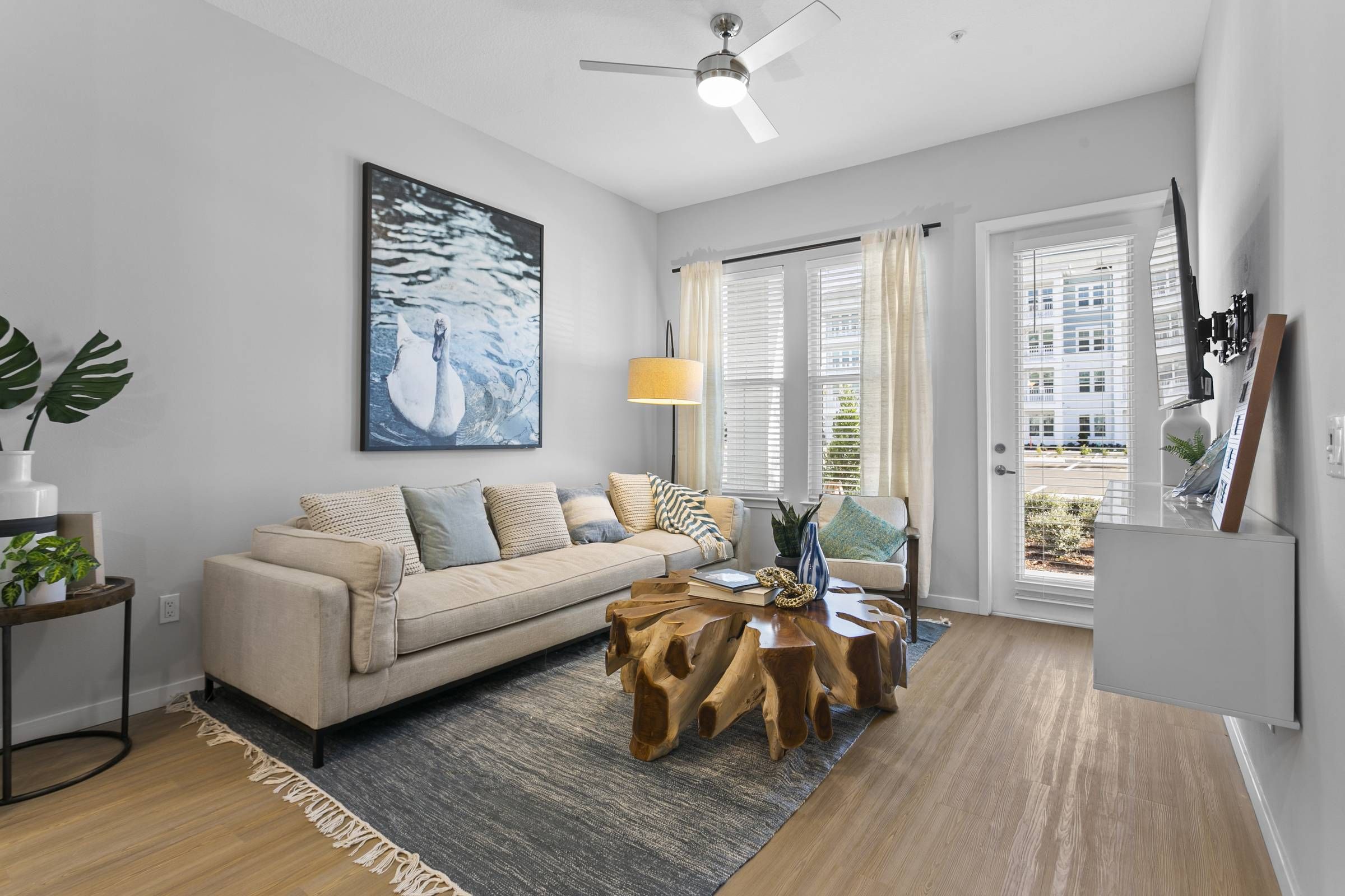 A spacious living room at Alta Belleair, furnished with a neutral-toned couch, artistic coffee table, and serene blue decorative elements, radiating a calming vibe.