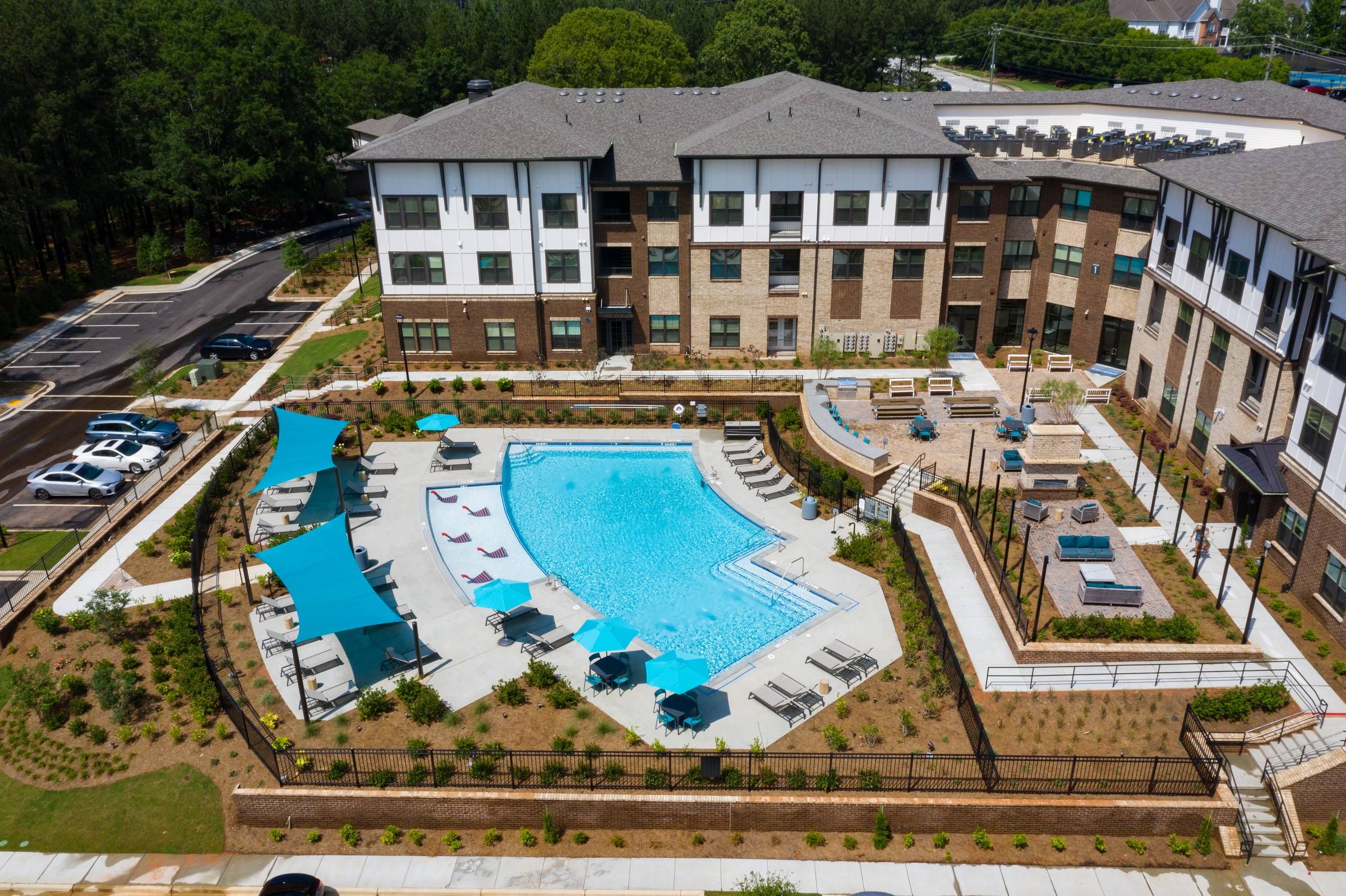 Overhead view of Alta Sugarloaf's community pool area flanked by apartment buildings, featuring aqua blue water and well-arranged patio furniture.