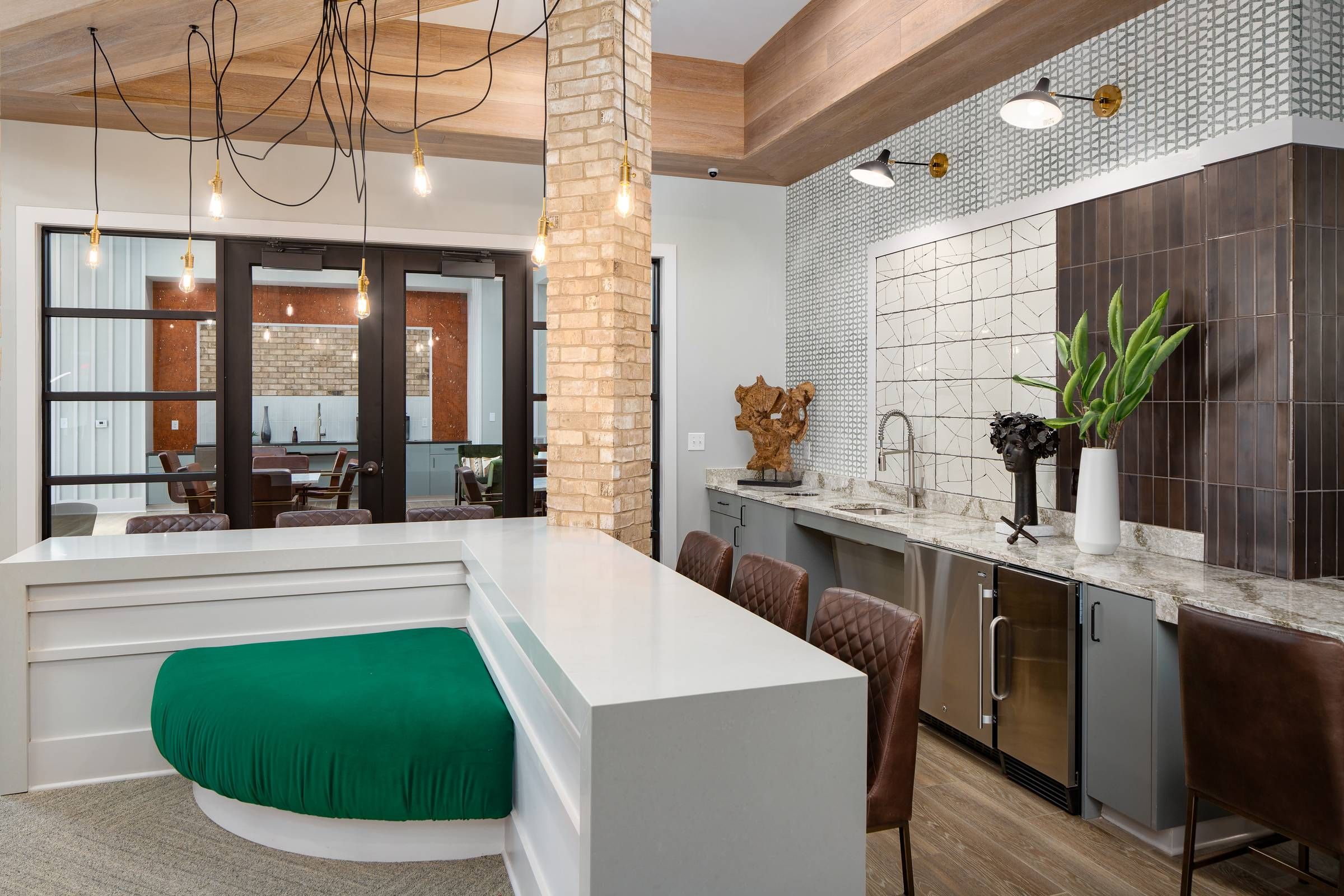 Alta Sugarloaf's modern kitchen and dining area with a white island countertop, leather bar stools, and elegant light fixtures, complemented by tasteful artwork and plants.