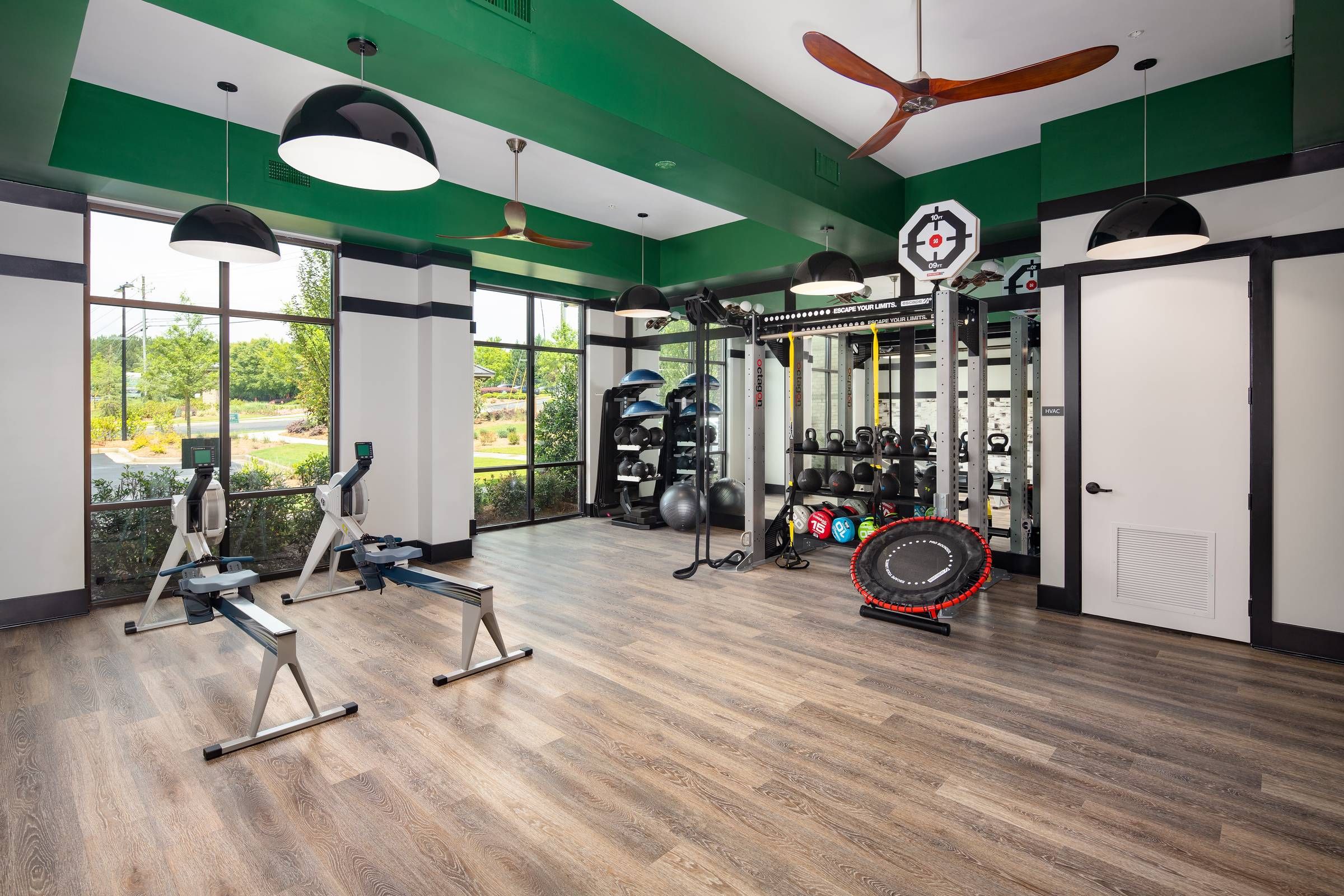 A well-equipped fitness center at Alta Sugarloaf with green accent walls, large windows, and a variety of exercise equipment.