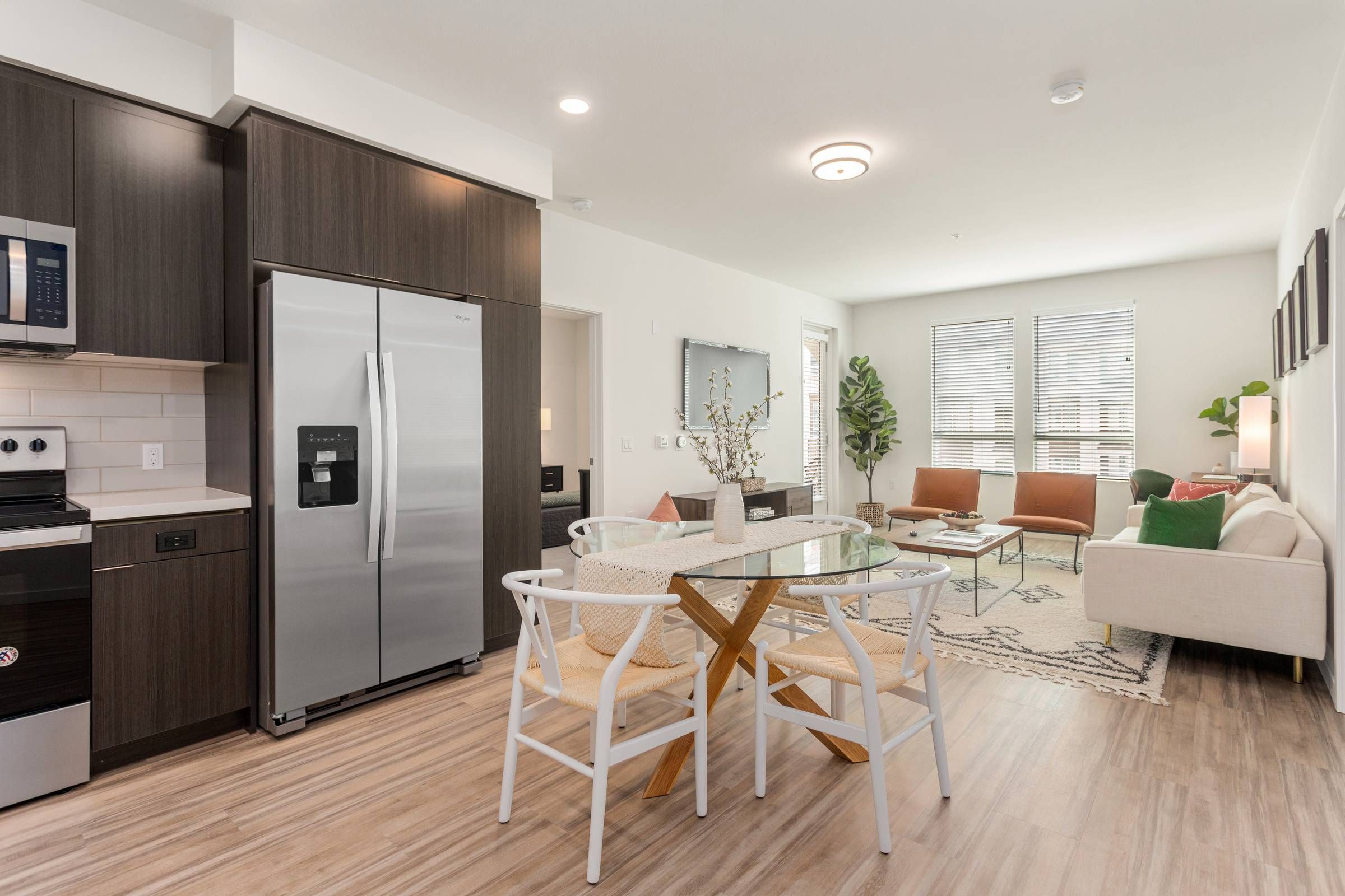 A well-appointed living space in Alta Upland includes a modern kitchen with dark wood cabinets, a round glass dining table, and a stylish living area with soft textures and neutral tones.