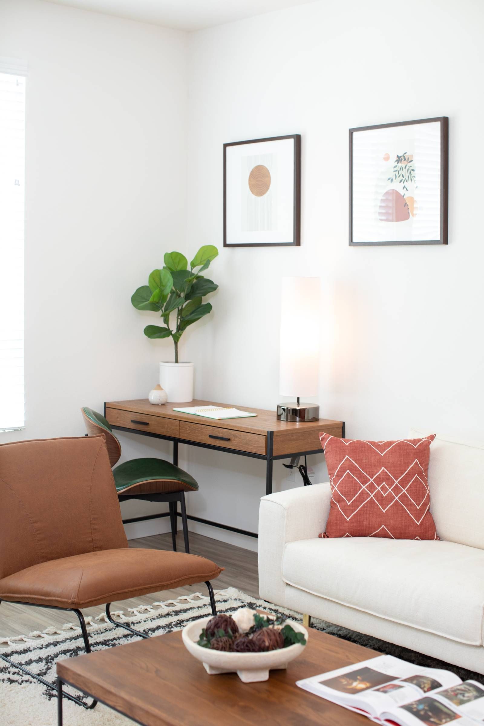 A cozy corner in an Alta Upland apartment, with a plush white sofa, terracotta leather chair, wooden furniture, and framed abstract artwork on the walls.