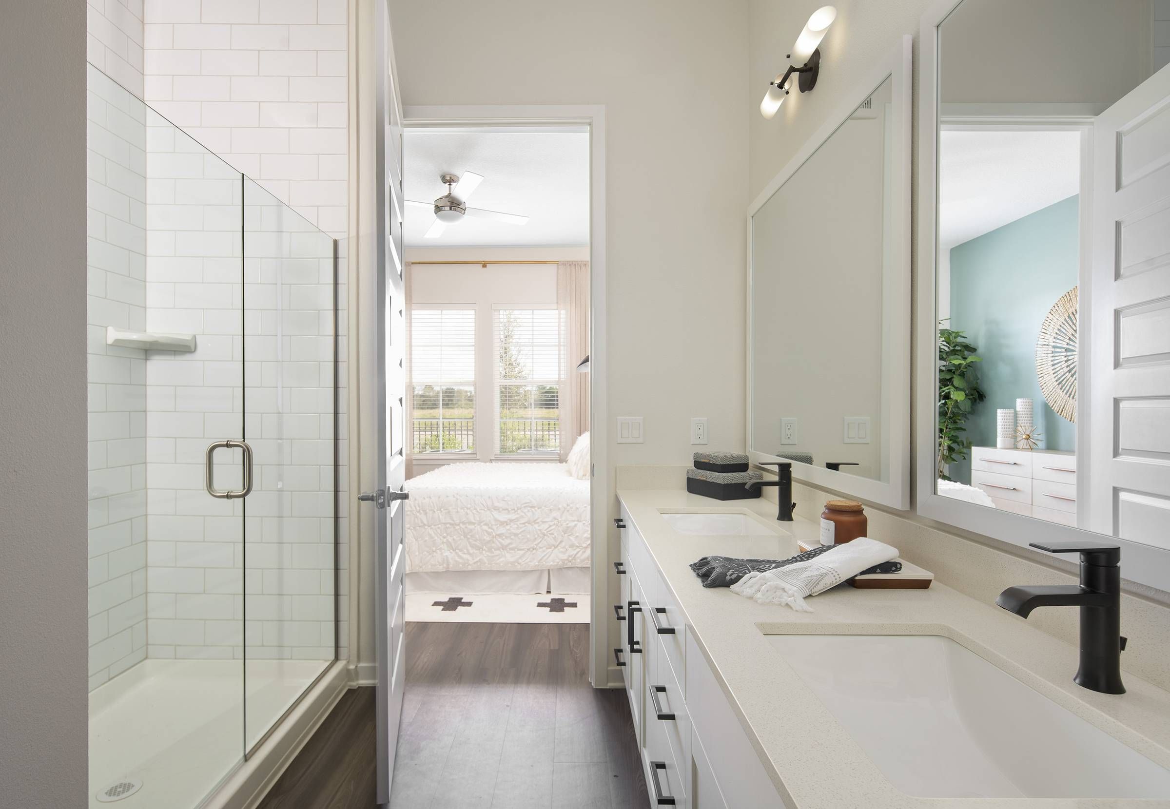 A modern and sleek bathroom in Alta Winter Garden with a glass-enclosed shower and a view into the adjoining bedroom.