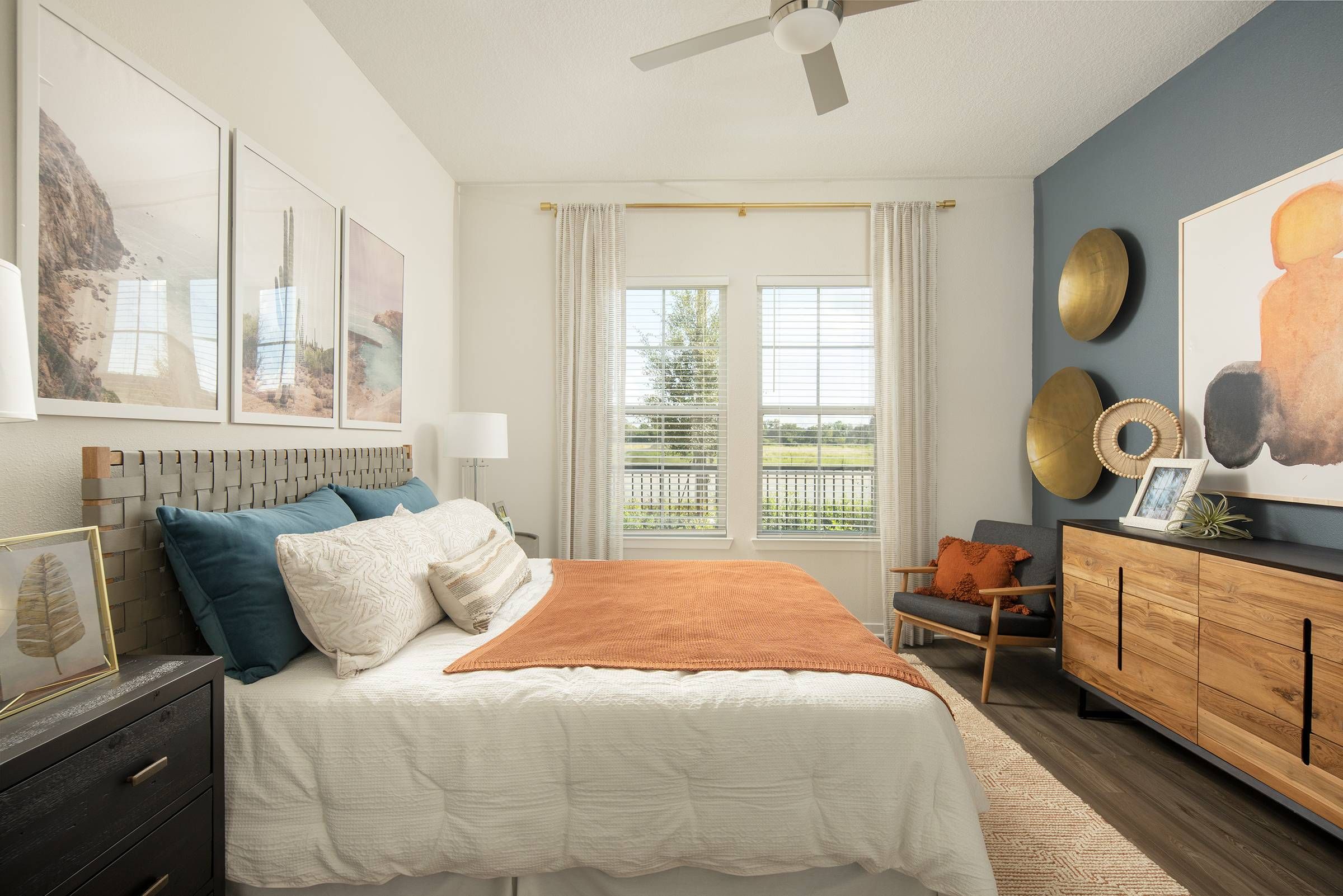 A cozy bedroom at Alta Winter Garden featuring a warm-toned bedspread, stylish wall decor, and views of the outdoors.