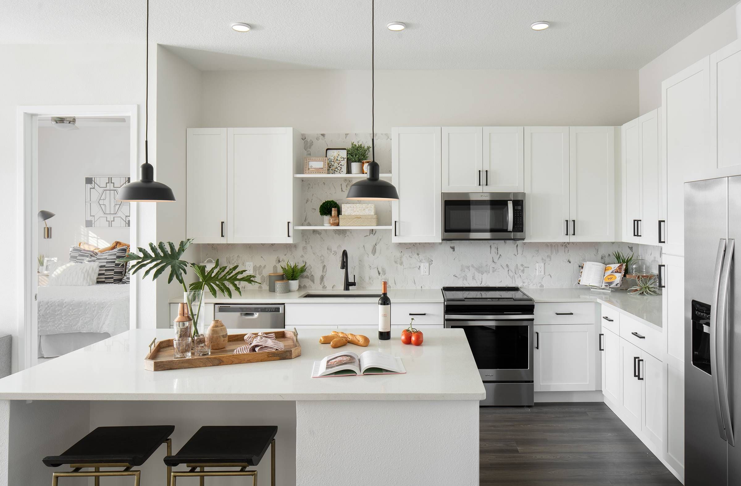 Modern kitchen in Alta Winter Garden featuring white cabinetry, stainless steel appliances, and a marble-patterned backsplash illuminated by pendant lights.