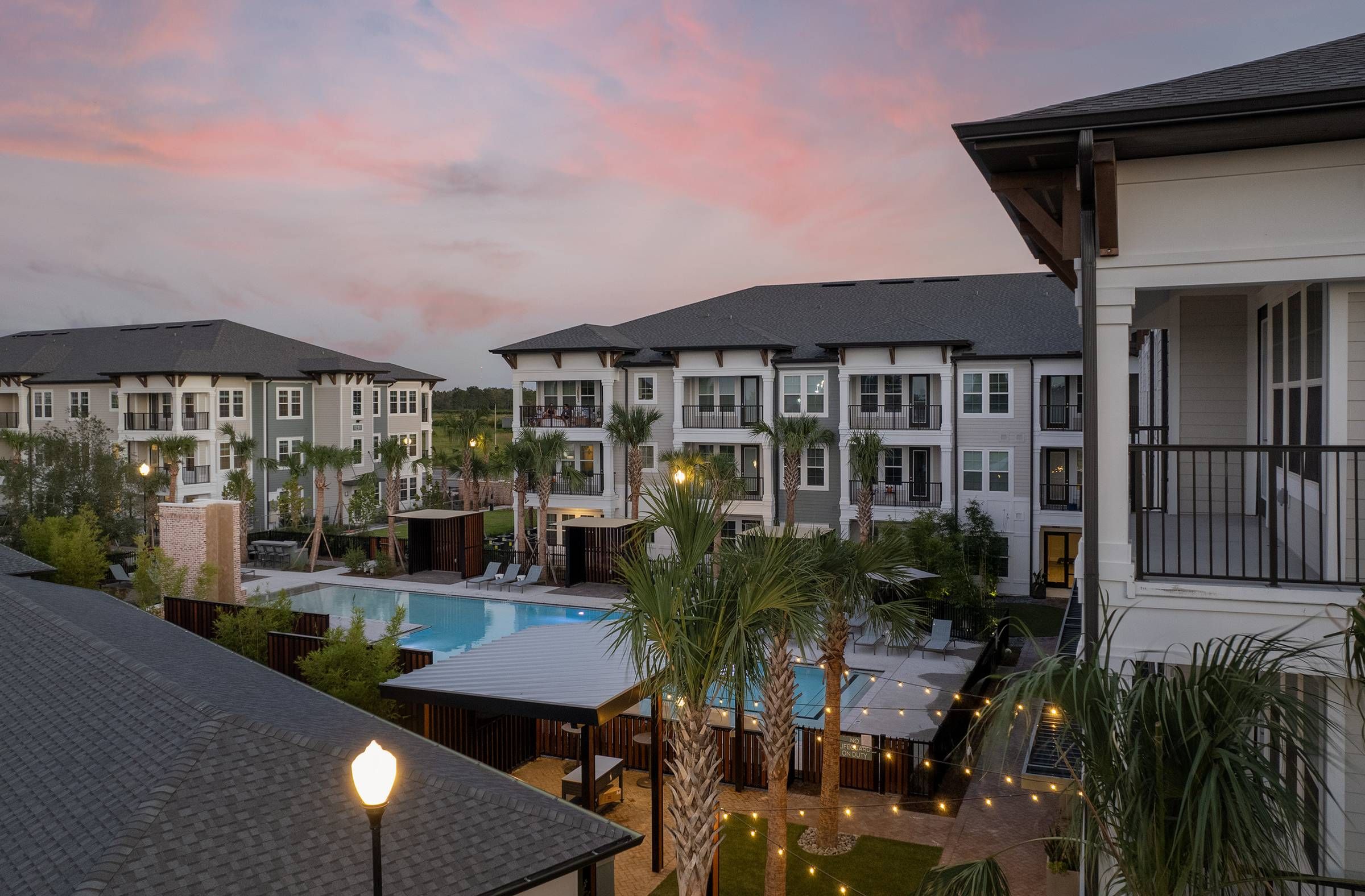 Dusk settles over the serene pool and deck area at Alta Winter Garden, accented by warm lighting and tropical landscaping.
