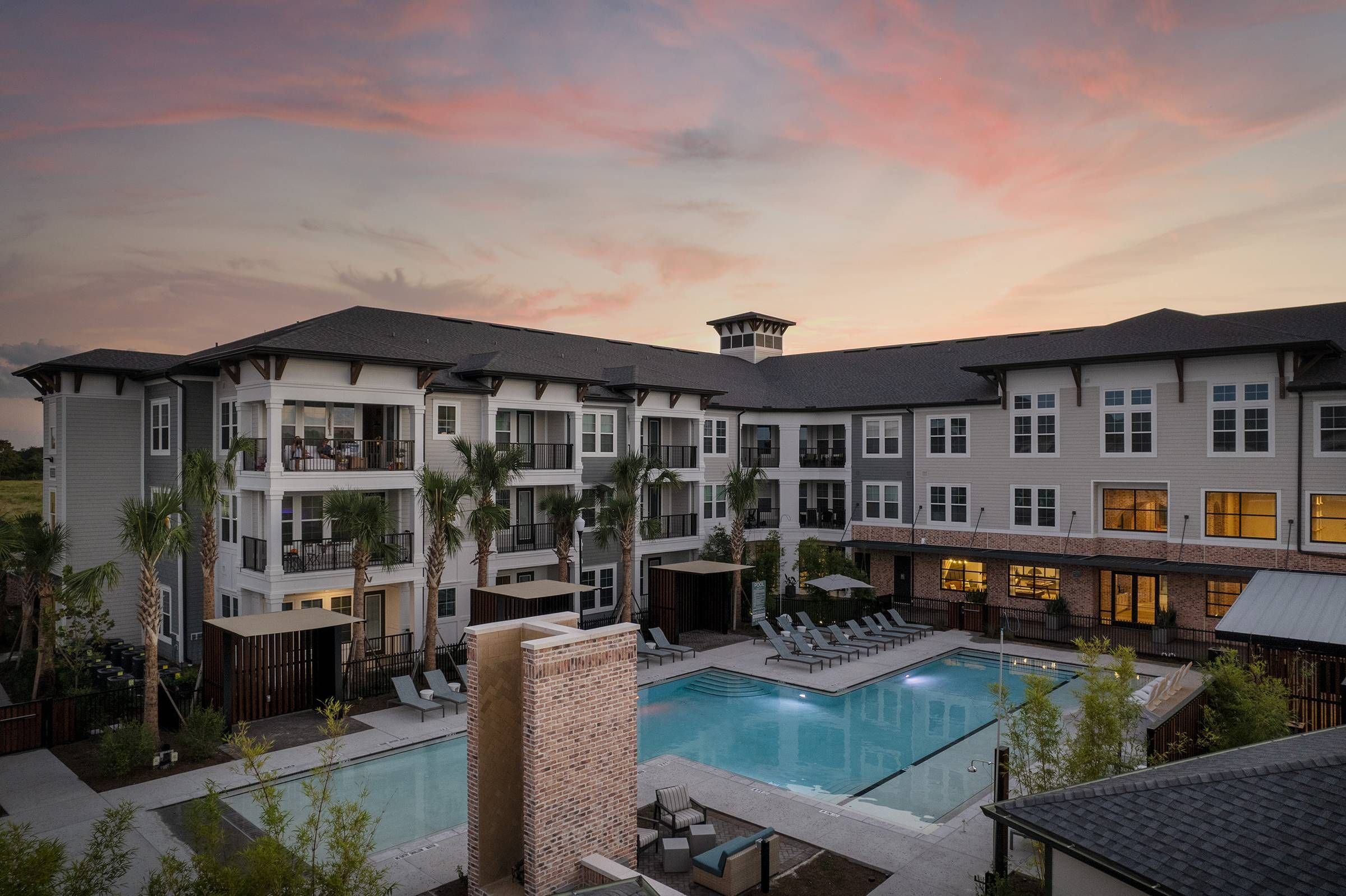 The lit pool and patio area of Alta Winter Garden offer a peaceful evening ambiance in an aerial view at dusk.