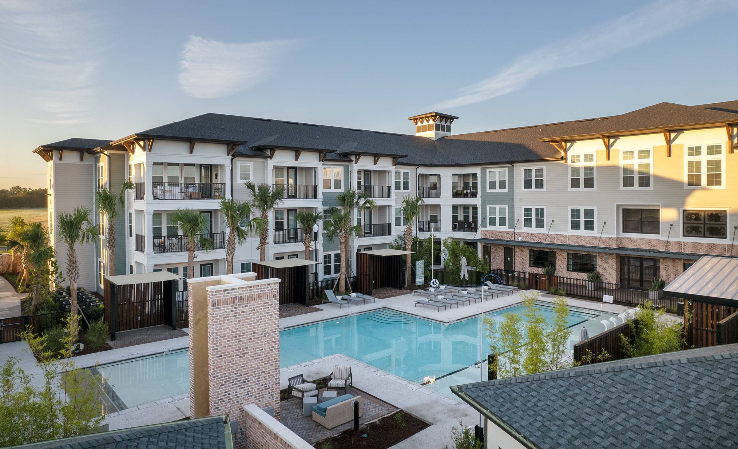 Sunrise view of Alta Winter Garden's elegant pool deck and loungers, nestled among modern apartment buildings.