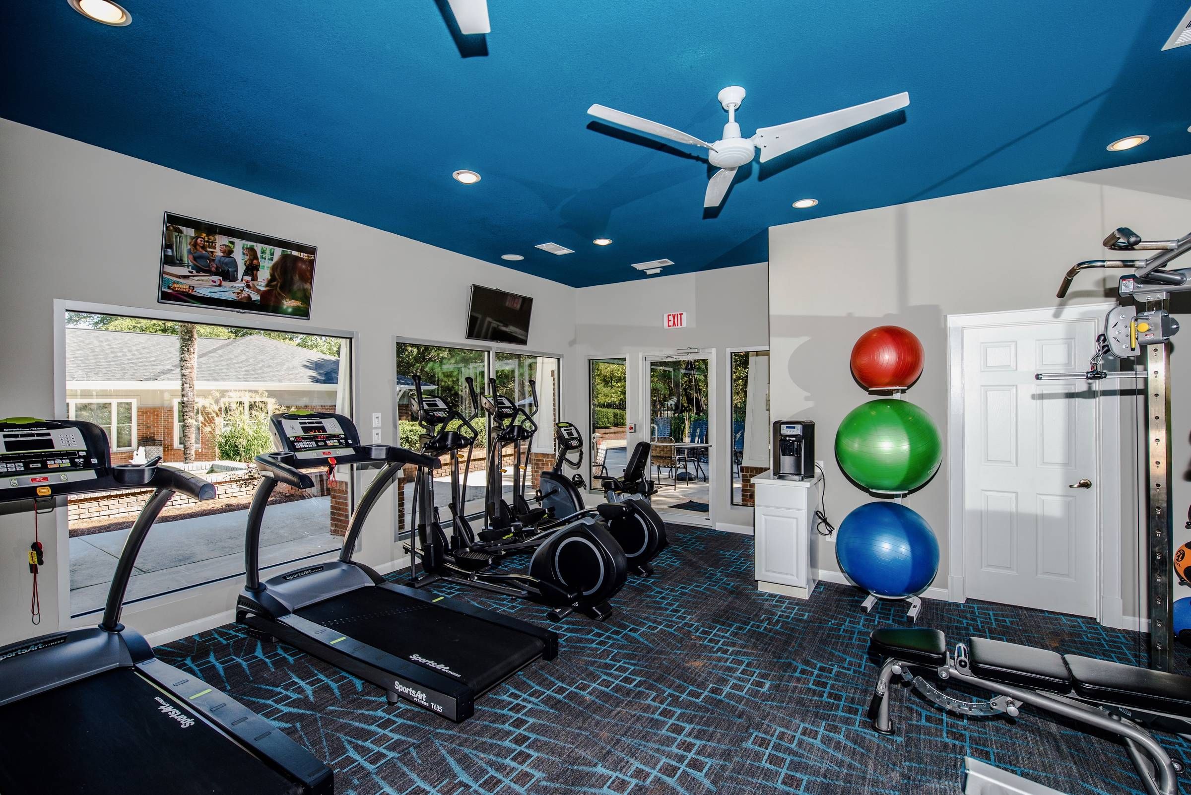 Altera Riverside fitness center with workout equipment and TVs.