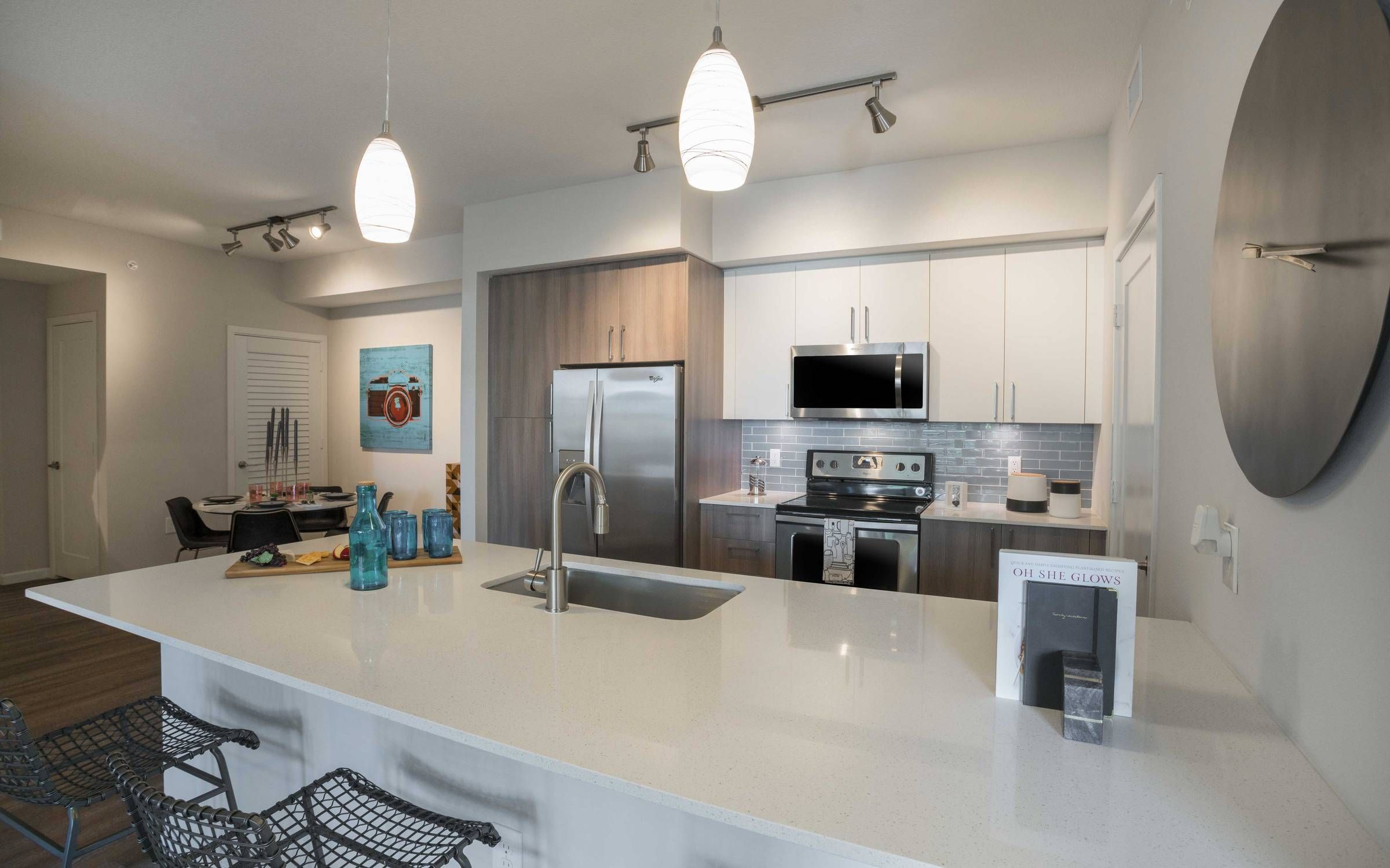 Delray Station kitchen with floating island, grey backsplash, ample cabinet space, and stainless steel appliances.