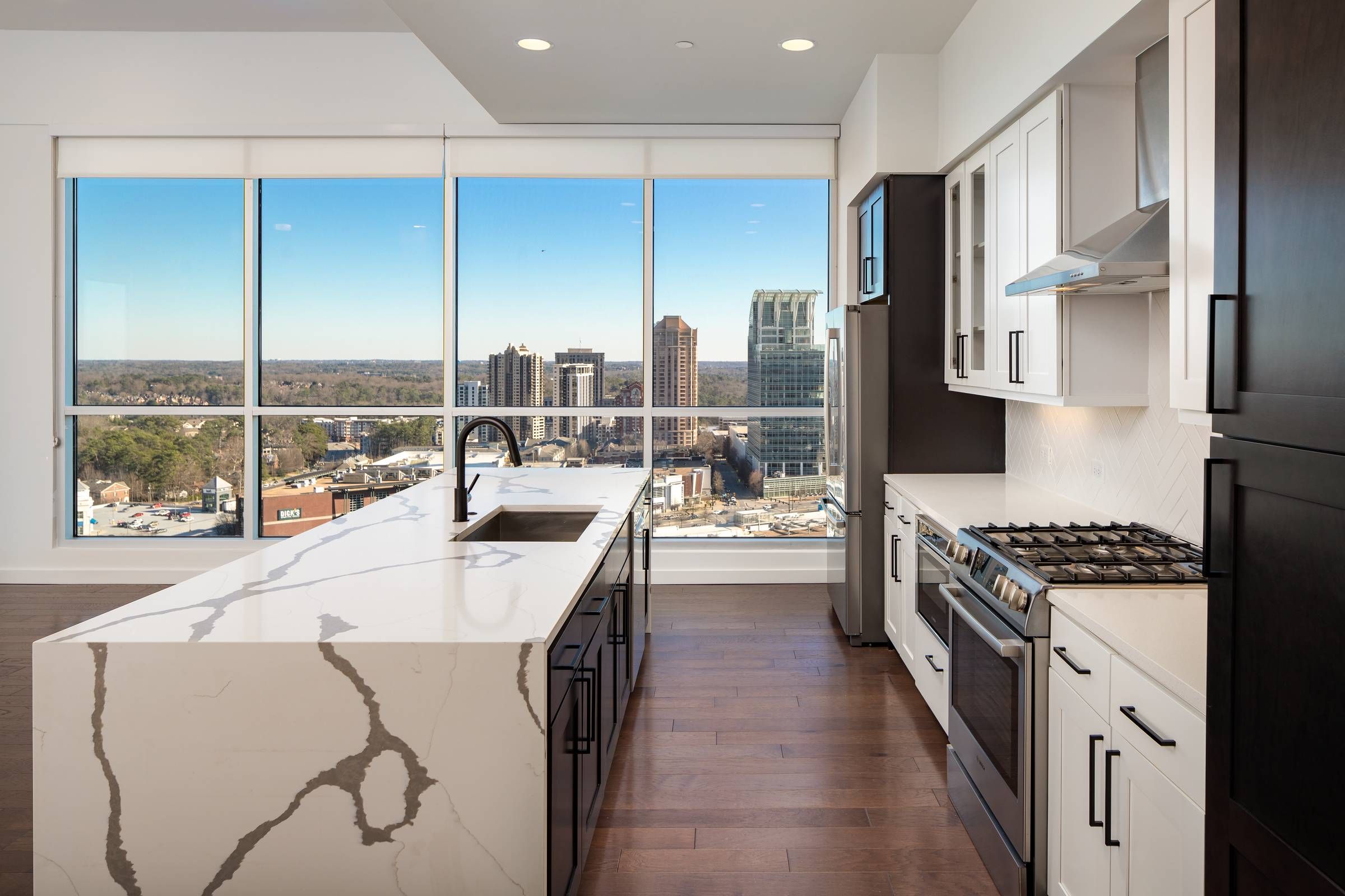 The Huntley kitchen with stylish marble counters overlooking city skyline out of a large window.