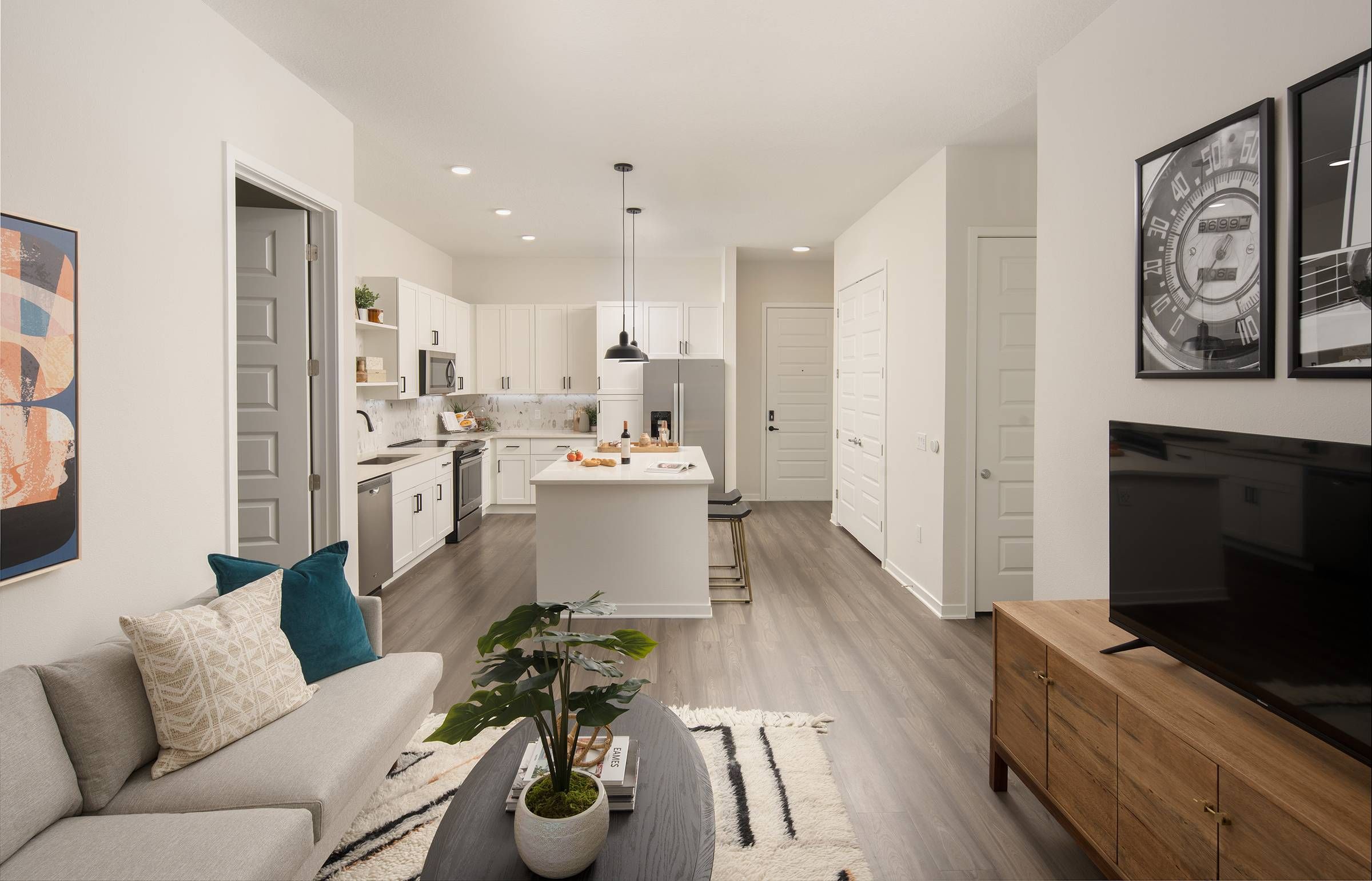 Interior view of Alta Winter Garden's two-bedroom model living room, with a grey sofa, patterned rug, and a decorative wall clock adding character to the space.