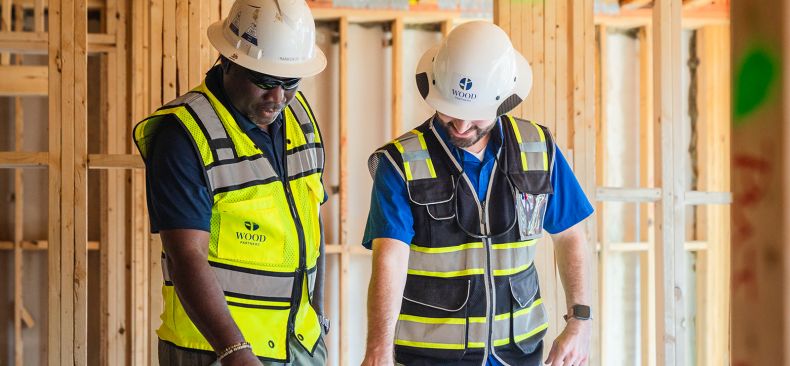 Group of construction workers review a set of plans on a table.