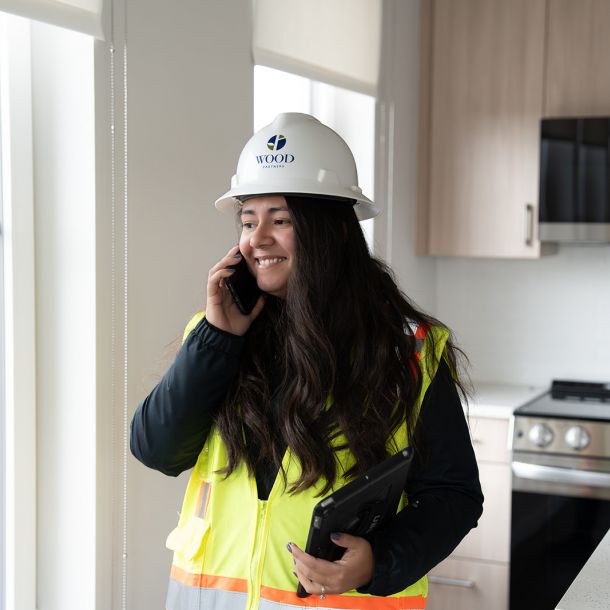Two construction workers stand in front of a large bulldozer at a construction site.