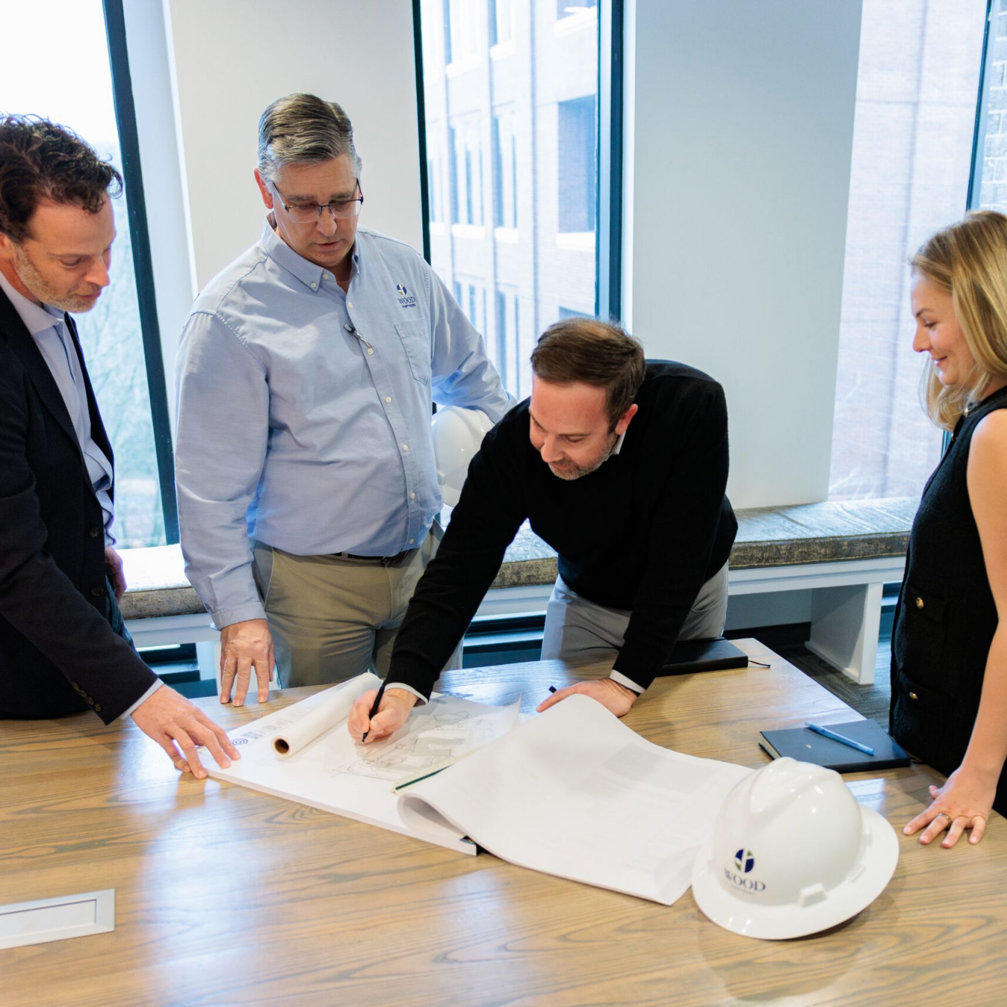 Back of construction workers in hard hats walking single file through a construction site