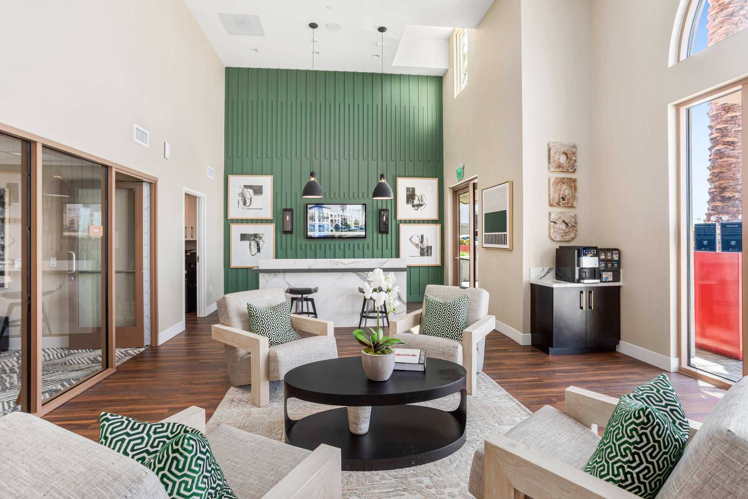 The welcoming lobby of Alta Upland boasts comfortable seating, chic decor, and a marble-topped coffee station against a vibrant green accent wall.