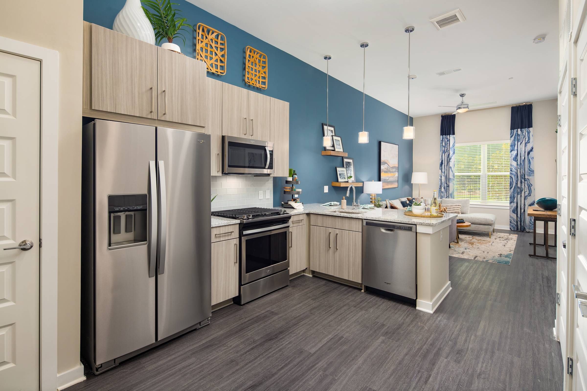 A contemporary kitchen in Alta Sugarloaf with sleek stainless-steel appliances, beige cabinets, and a breakfast bar opening into a cozy living area.