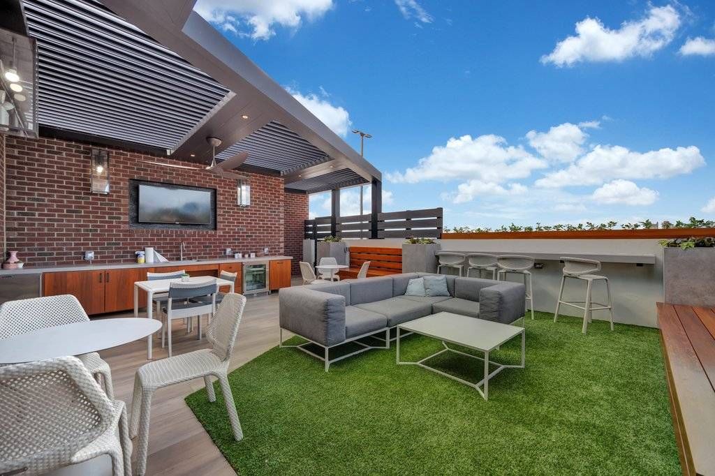 Alta Purl outdoor community kitchen and lounge area with astro-turf and ample seating on rooftop.