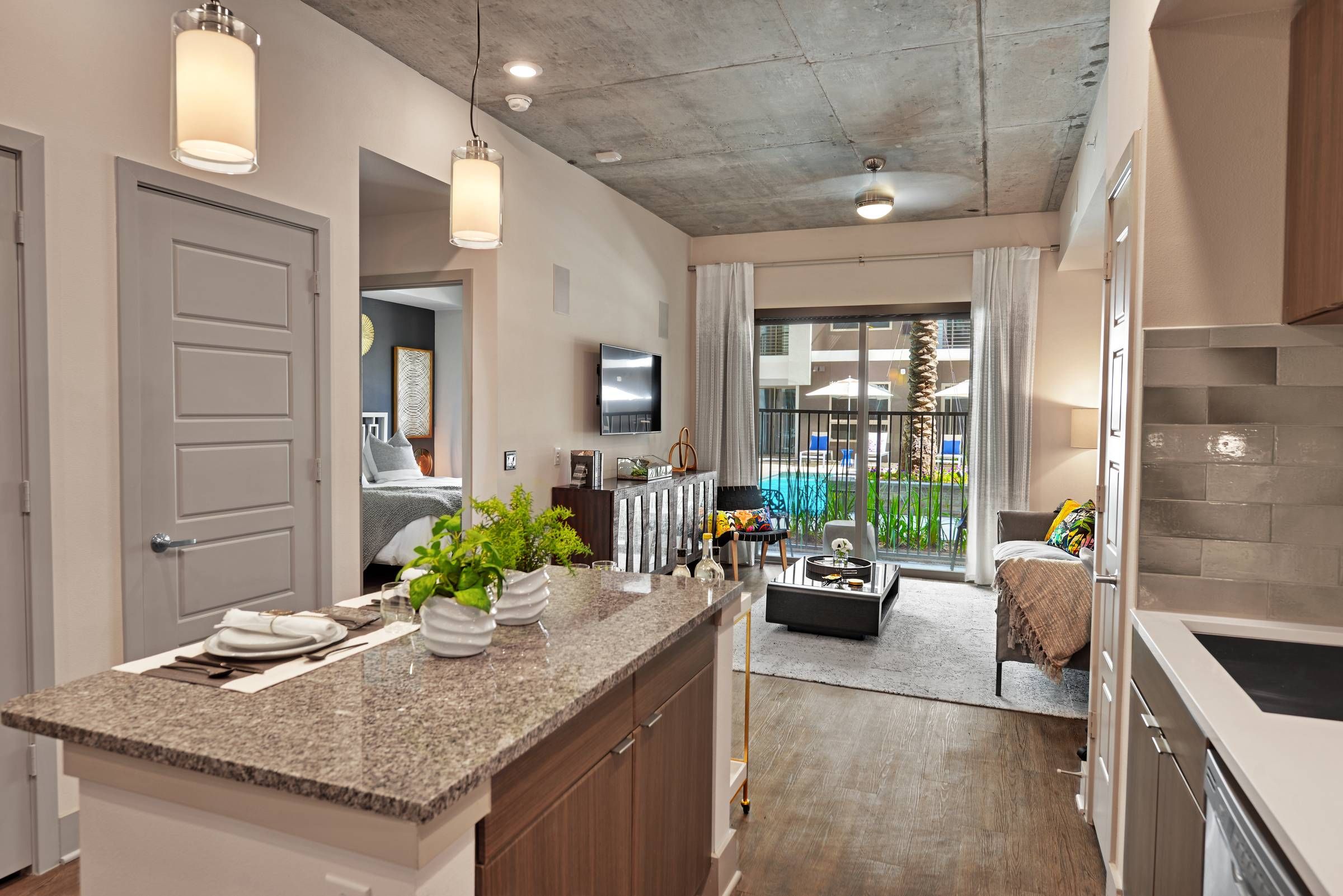 A modern kitchen at Alta West Gray featuring dark wood cabinets, stainless steel appliances, and a granite countertop with a breakfast bar.