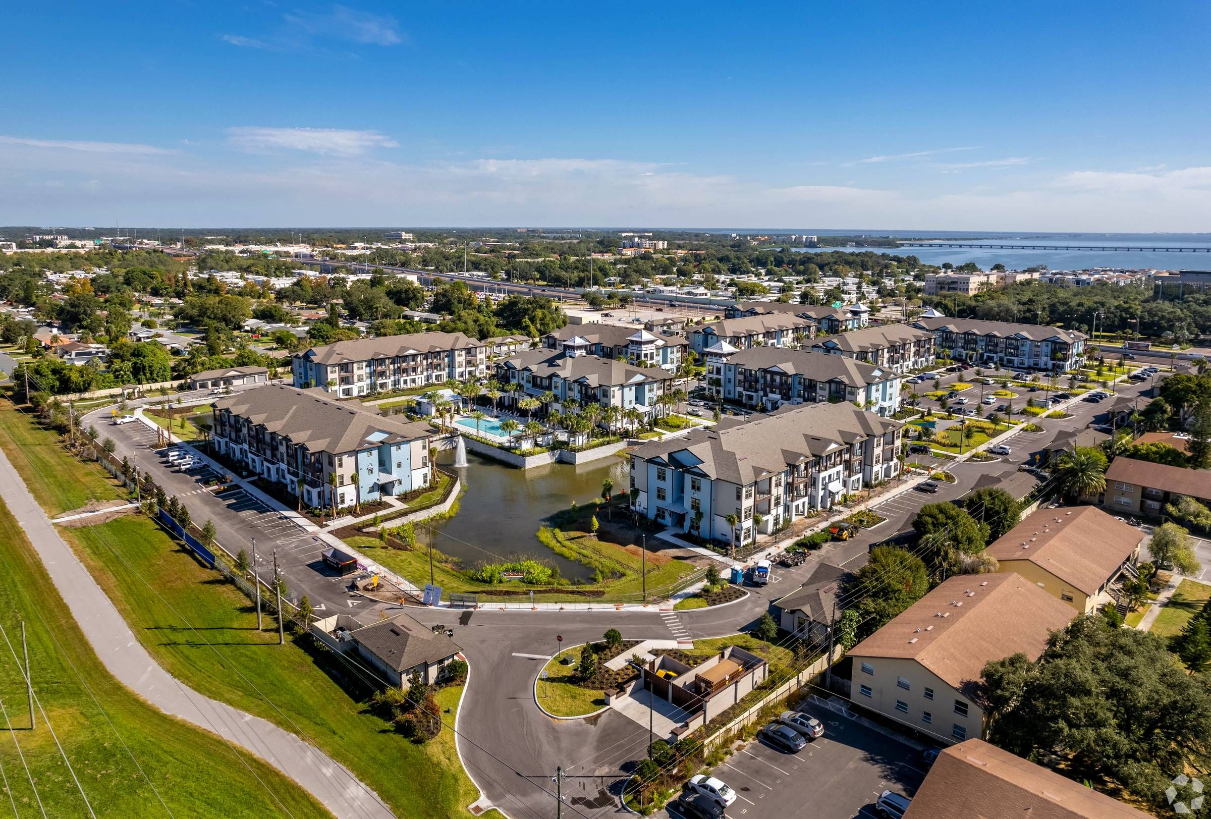 An aerial view of the expansive Alta Clearwater complex reveals multiple buildings surrounded by lush greenery, roads, and a clear blue sky.