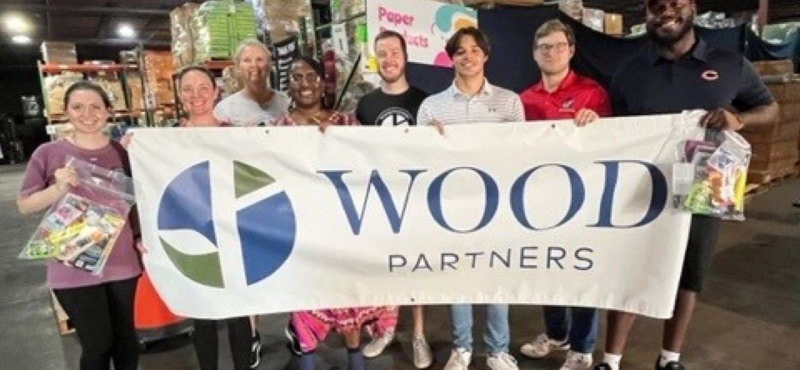 Co-workers hold up a large banner with Wood Partners logo