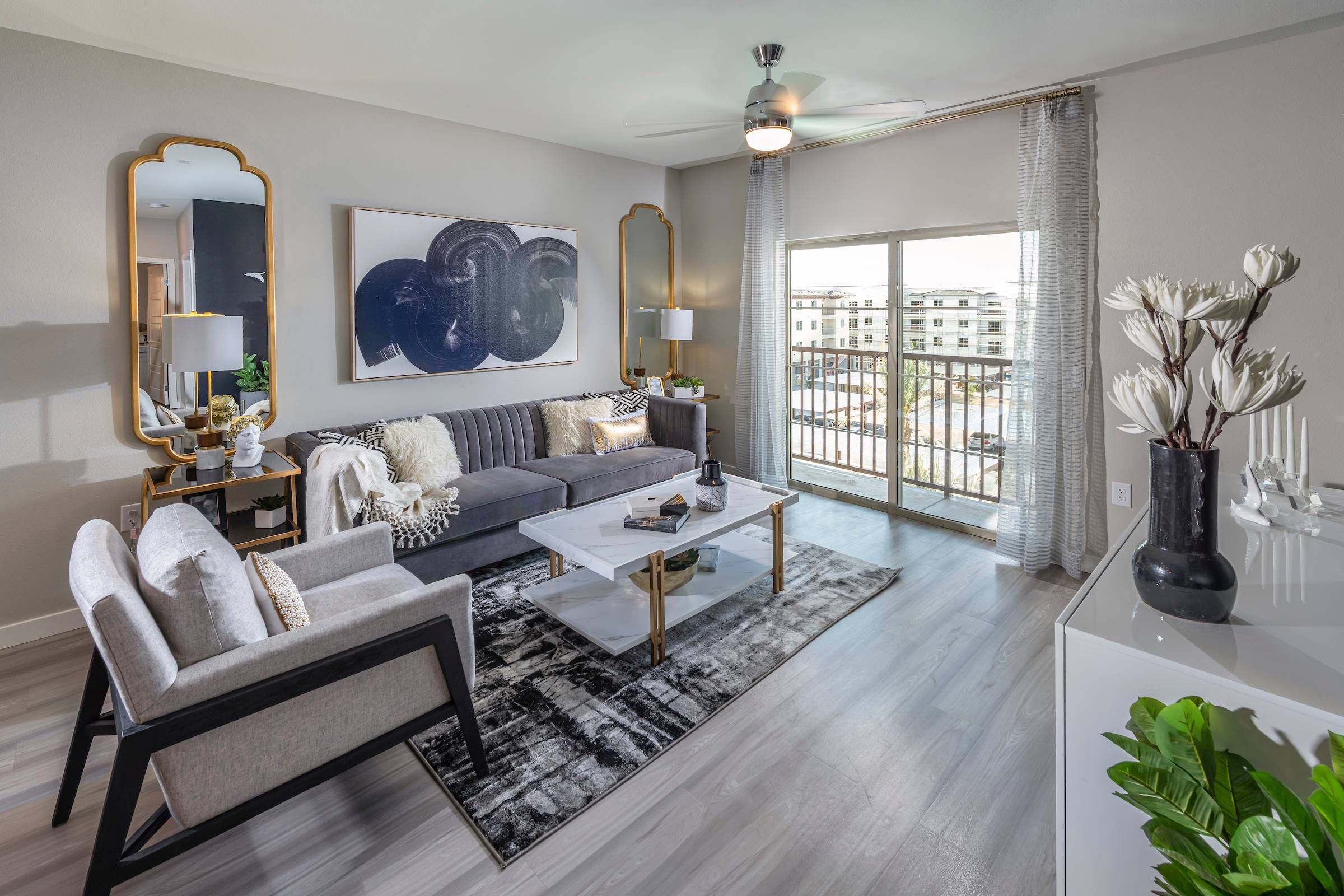 Apartment living room in Alta Southern Highlands that features a grey sofa, golden mirrors, and chic home decor.