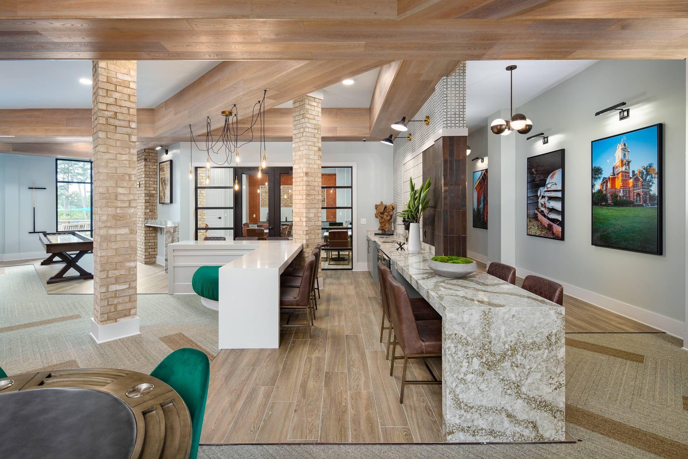 Inside Alta Sugarloaf, a spacious communal area with a kitchen island, contemporary seating, and artistic decor illuminated by natural and stylish lighting fixtures.