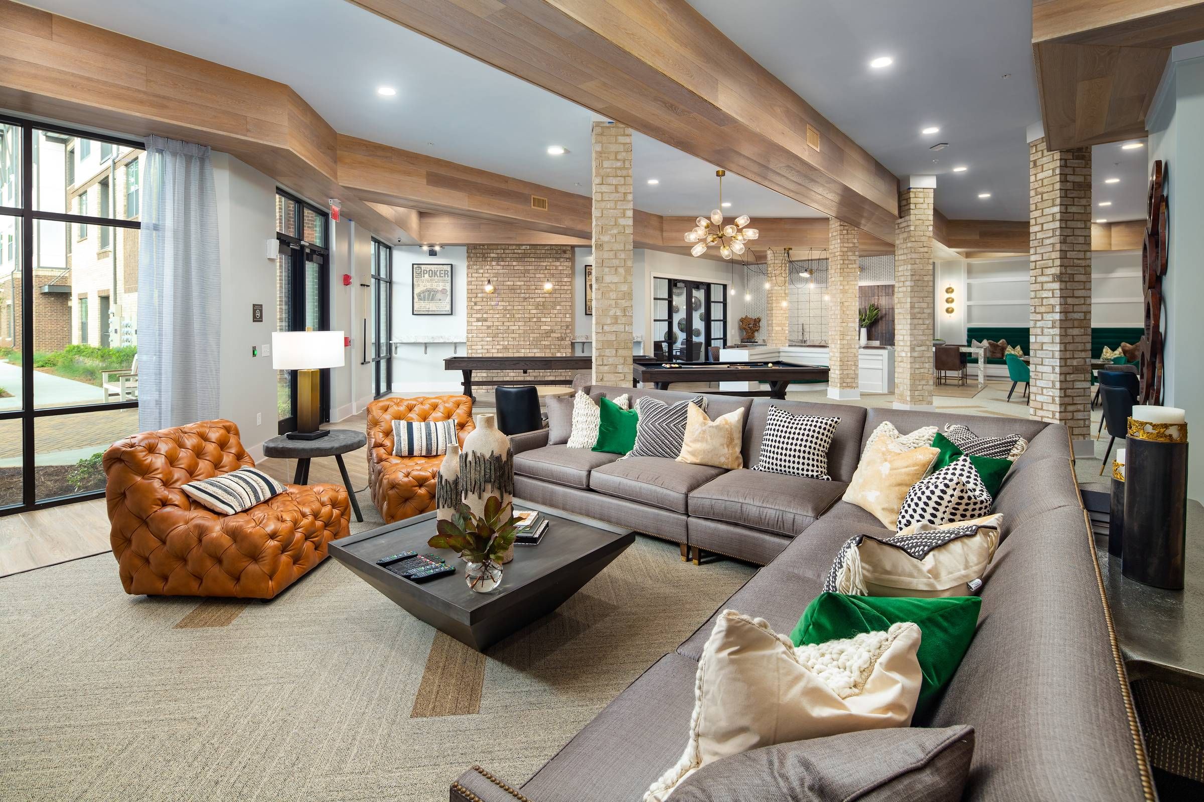 An elegantly furnished lounge area at Alta Sugarloaf featuring plush sofas, tufted leather armchairs, and modern decor accents under warm lighting.