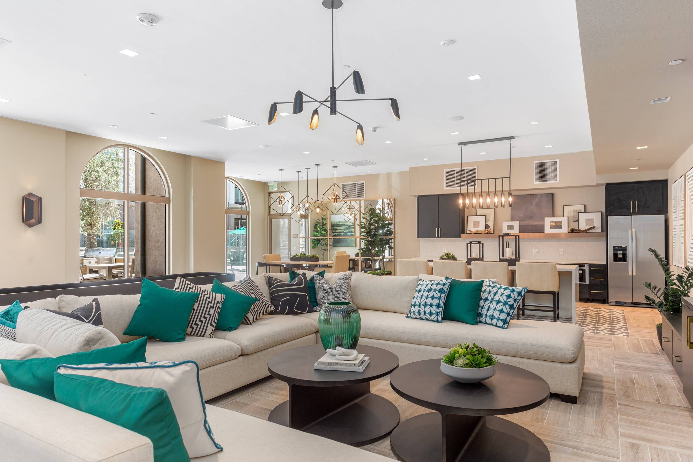 The inviting interior of Alta Upland combines a spacious living area with an integrated kitchen, distinguished by tall ceilings and elegant light fixtures.