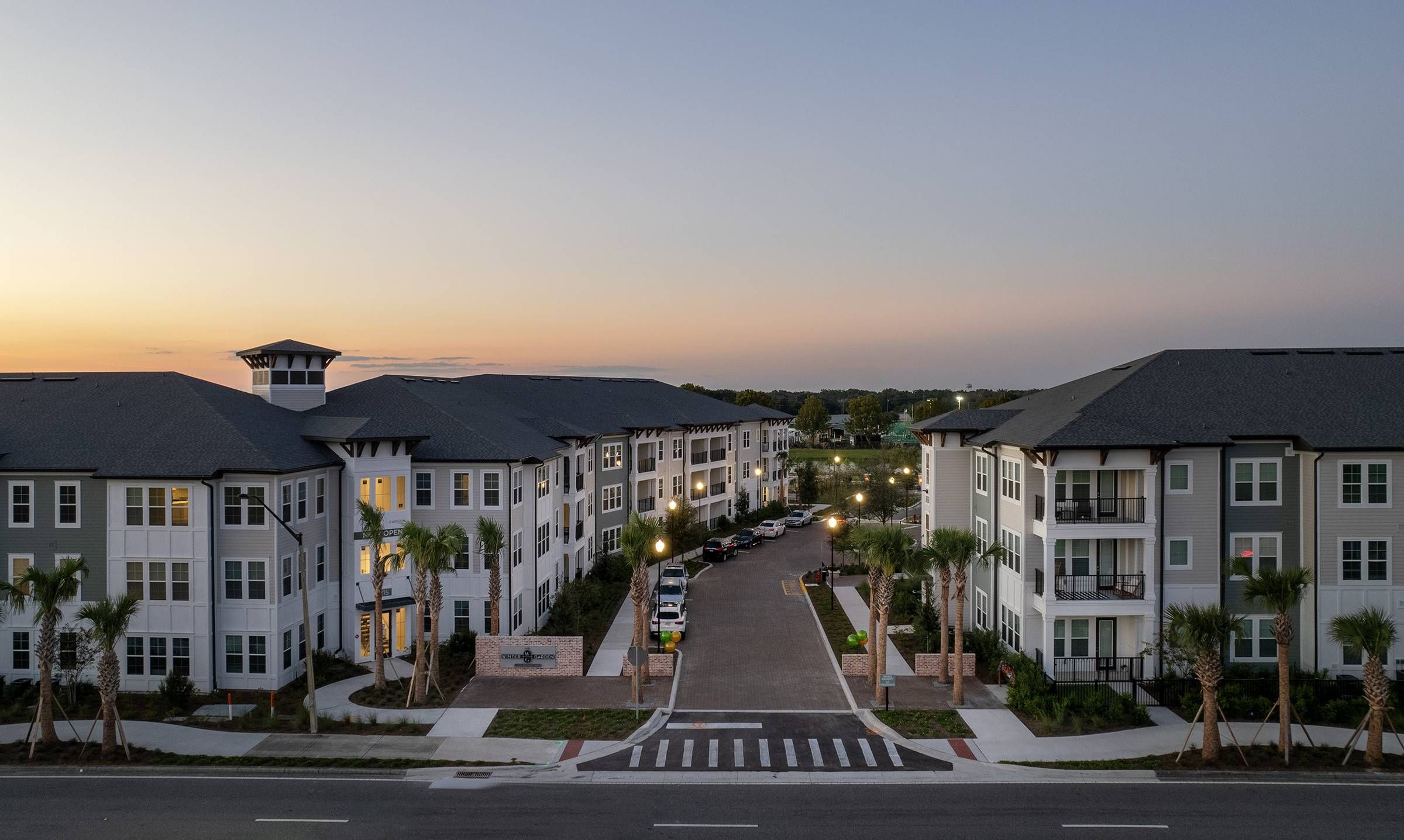 Twilight view of Alta Winter Garden, with the apartment complex illuminated under a fading sky.