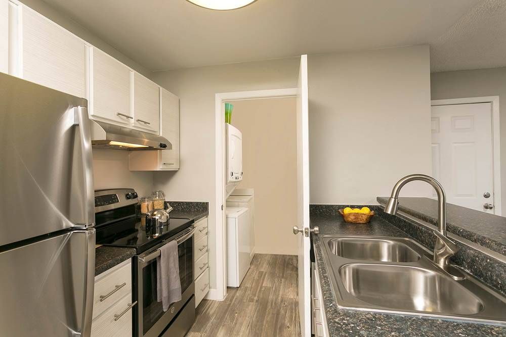 The Grove at City Center kitchen with stainless steel appliances, granite countertops, and entrance to laundry room.