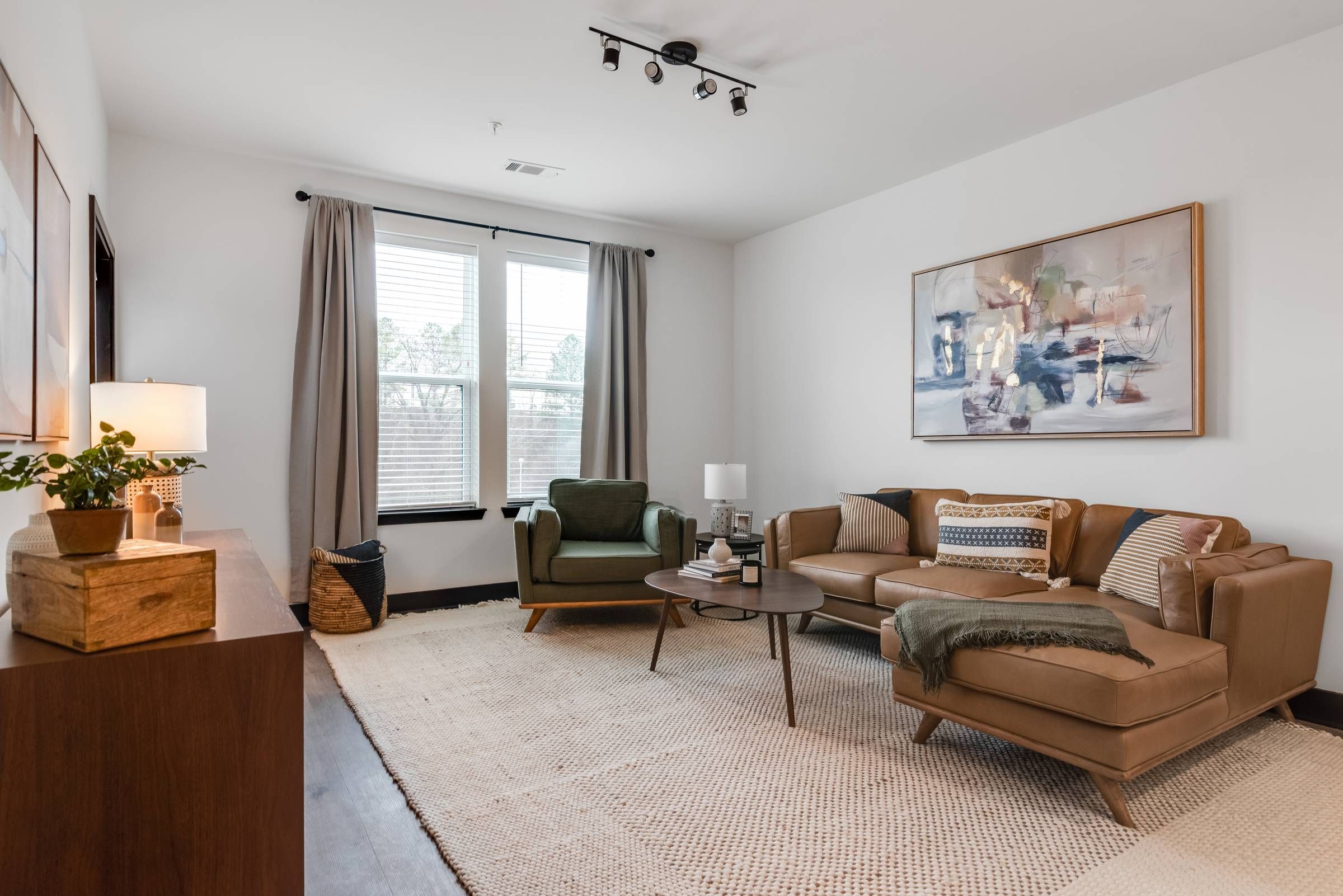 Alta Riverwalk spacious living room with large window, wood floors, and a large rug.