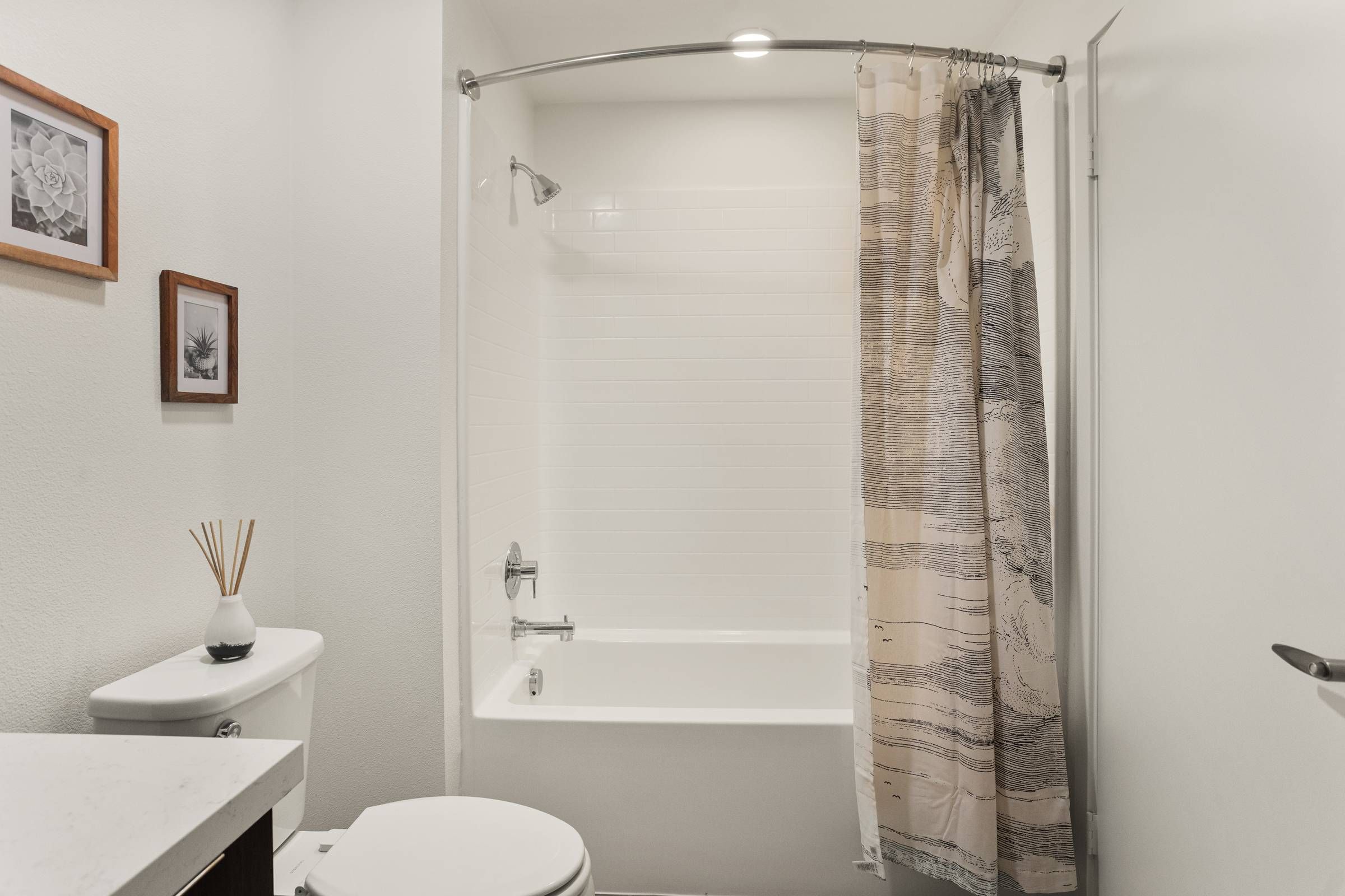 The spacious and stylish bathroom in Alta Upland features a clean design with subway tiles, a full bathtub, and chic framed artwork.