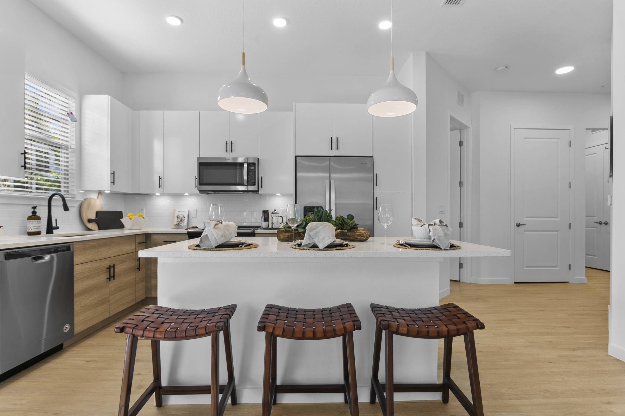 Alta Clearwater's open-concept kitchen features modern lighting and a welcoming breakfast bar.