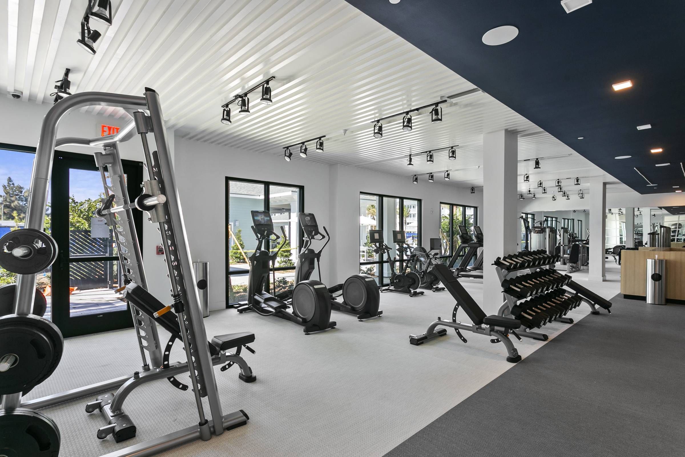 Alta Belleair's well-equipped fitness center, featuring state-of-the-art exercise machines and ample natural light filtering through floor-to-ceiling windows.