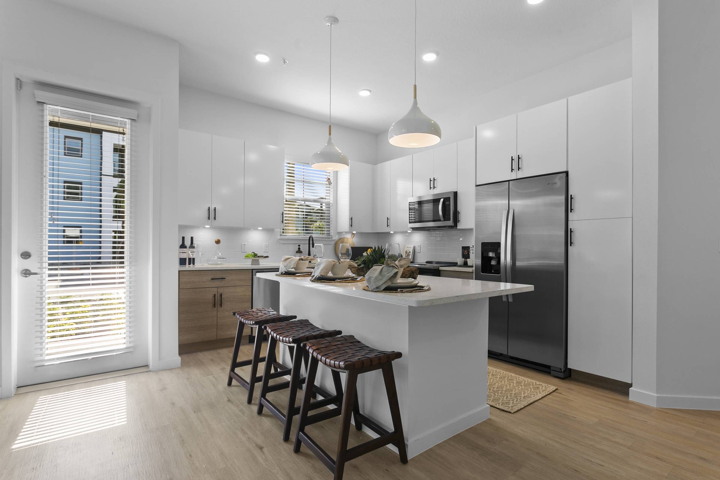 A bright kitchen with white cabinets, stainless steel appliances, and bar seating at Alta Clearwater.
