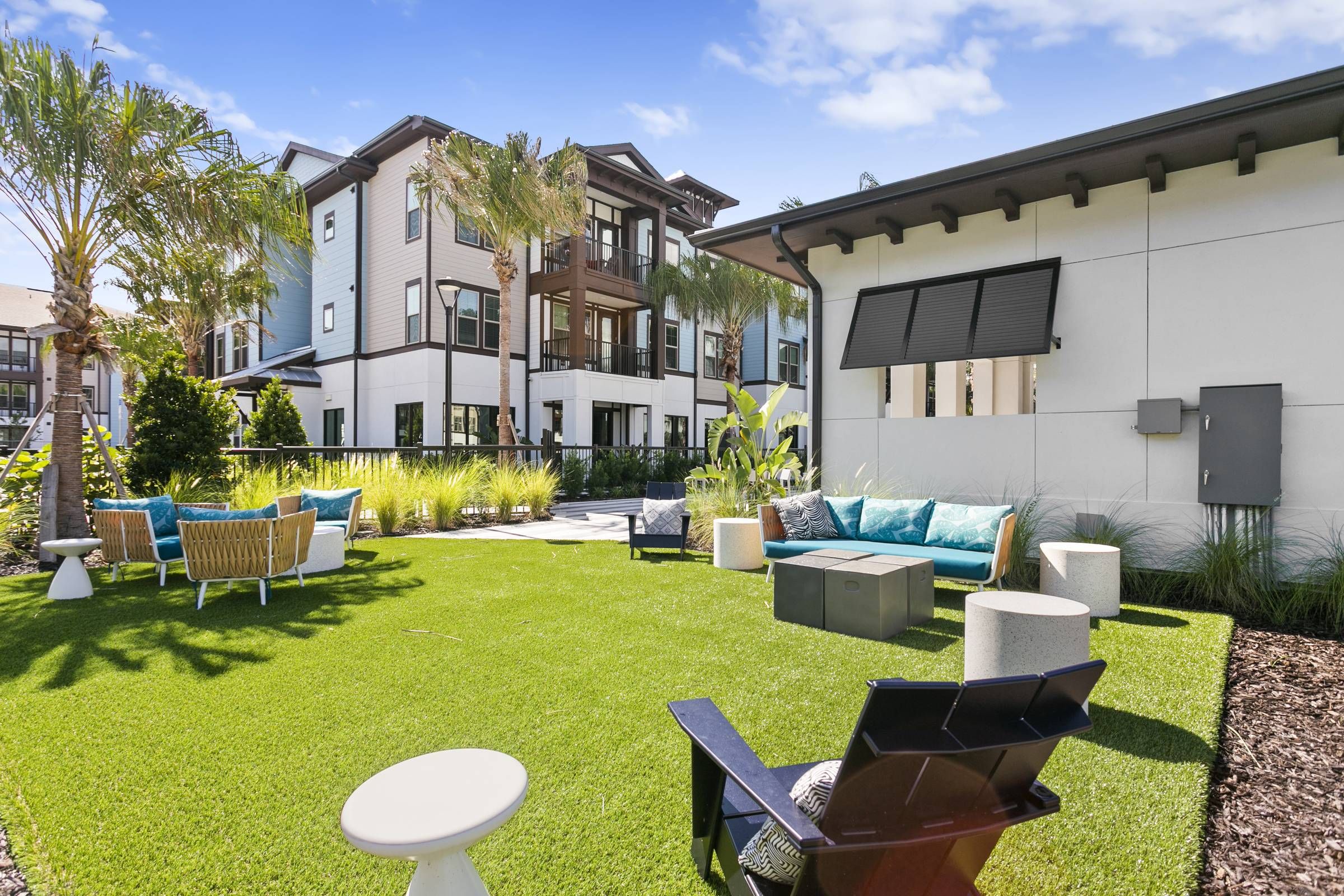 Alta Clearwater's communal backyard features a neatly manicured lawn with contemporary outdoor furniture, perfect for social gatherings.