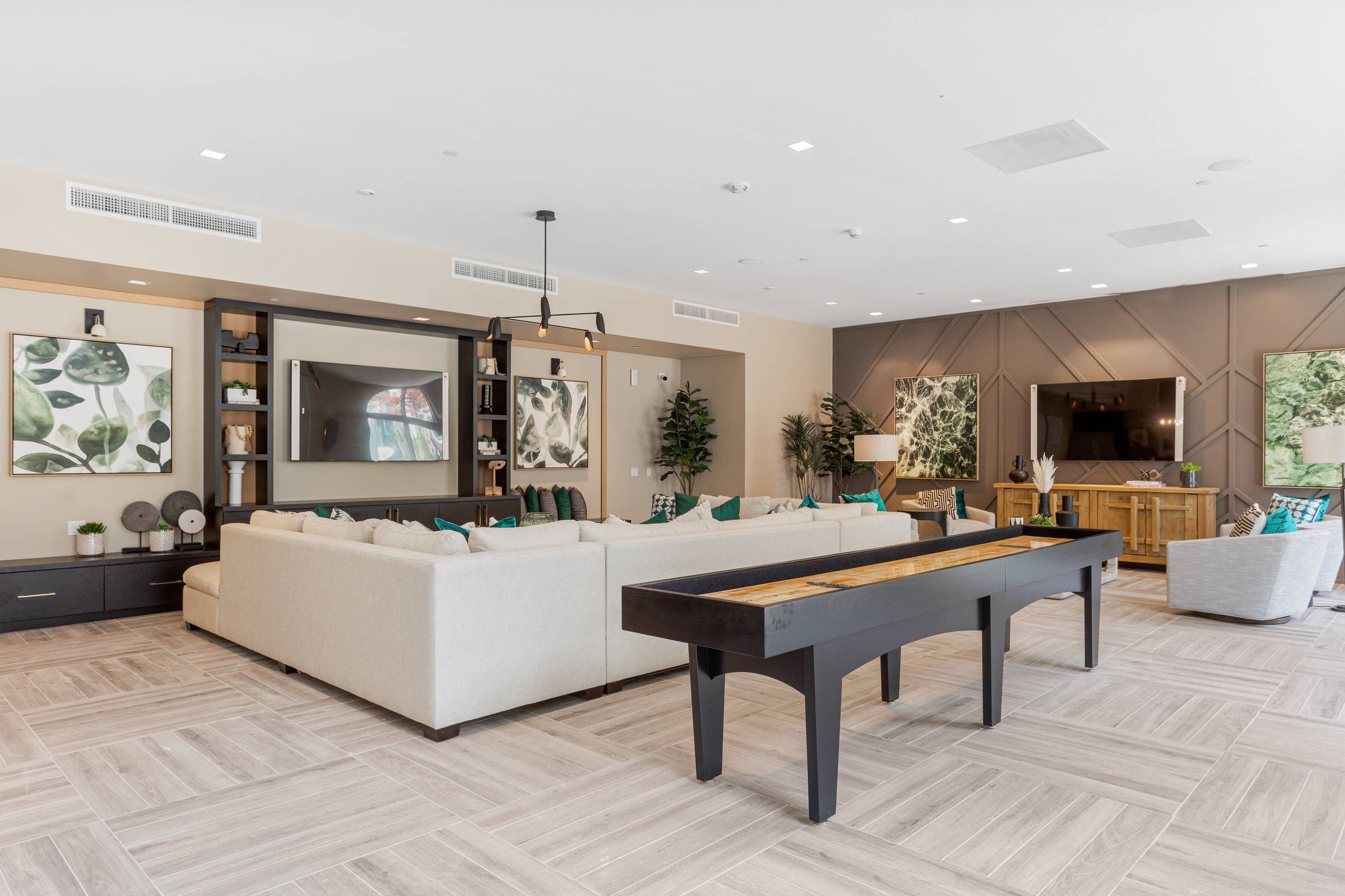 The stylish community room at Alta Upland exudes comfort with its cream-colored sectional, patterned cushions, and round coffee tables, creating an inviting space for relaxation.